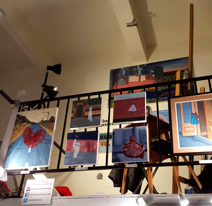 View of my bannister hung with paintings; my easel and workspace behind. 