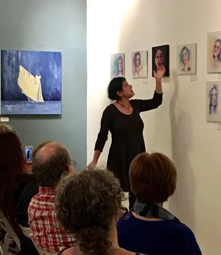Miki Berman explains her watercolor portraits (my painting "Phenomenal Woman" on the gray wall behind her). 
