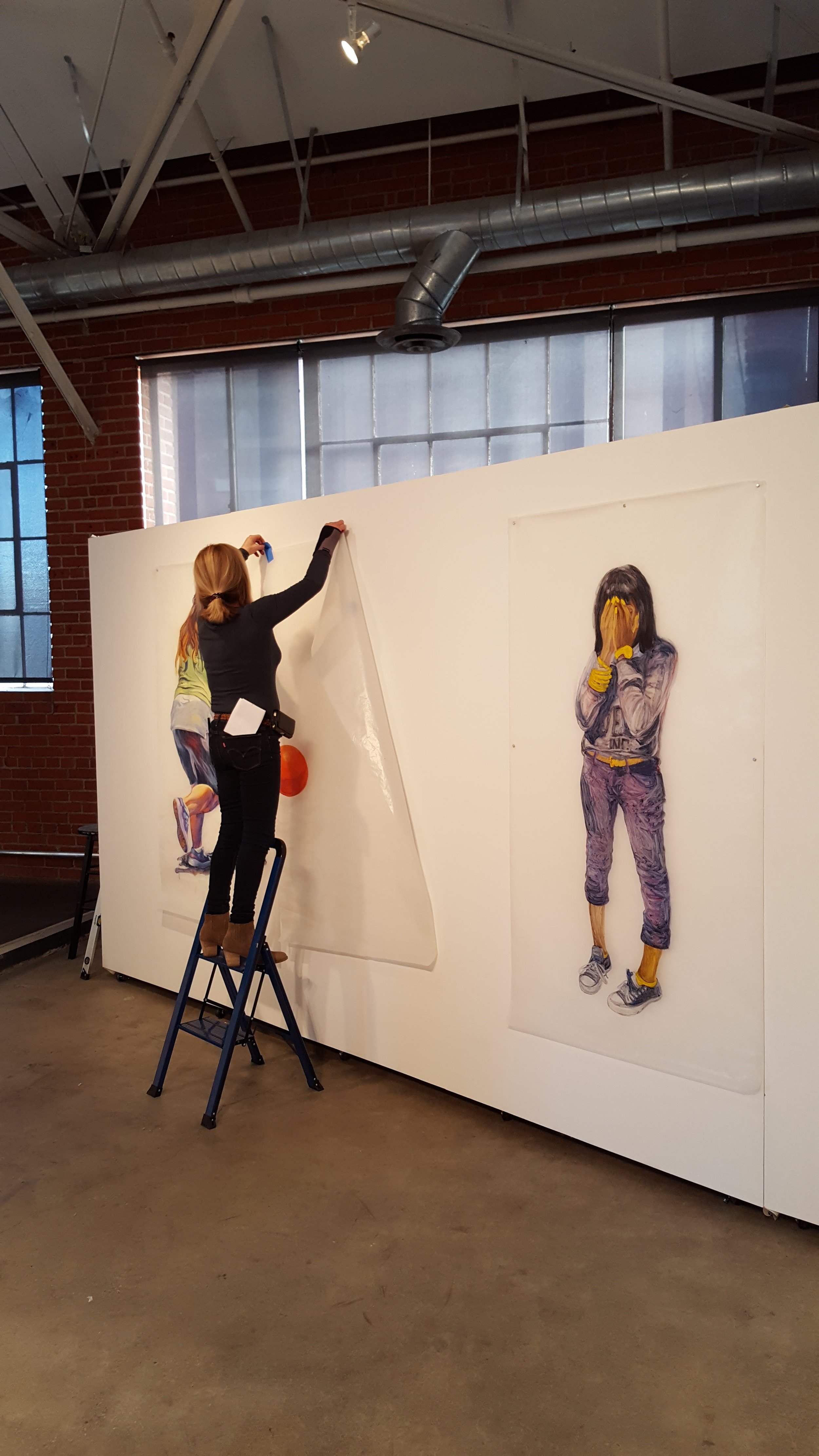 Deborah Decker hanging her paintings on glassene. | Photo credit: C. Rasmussen. 