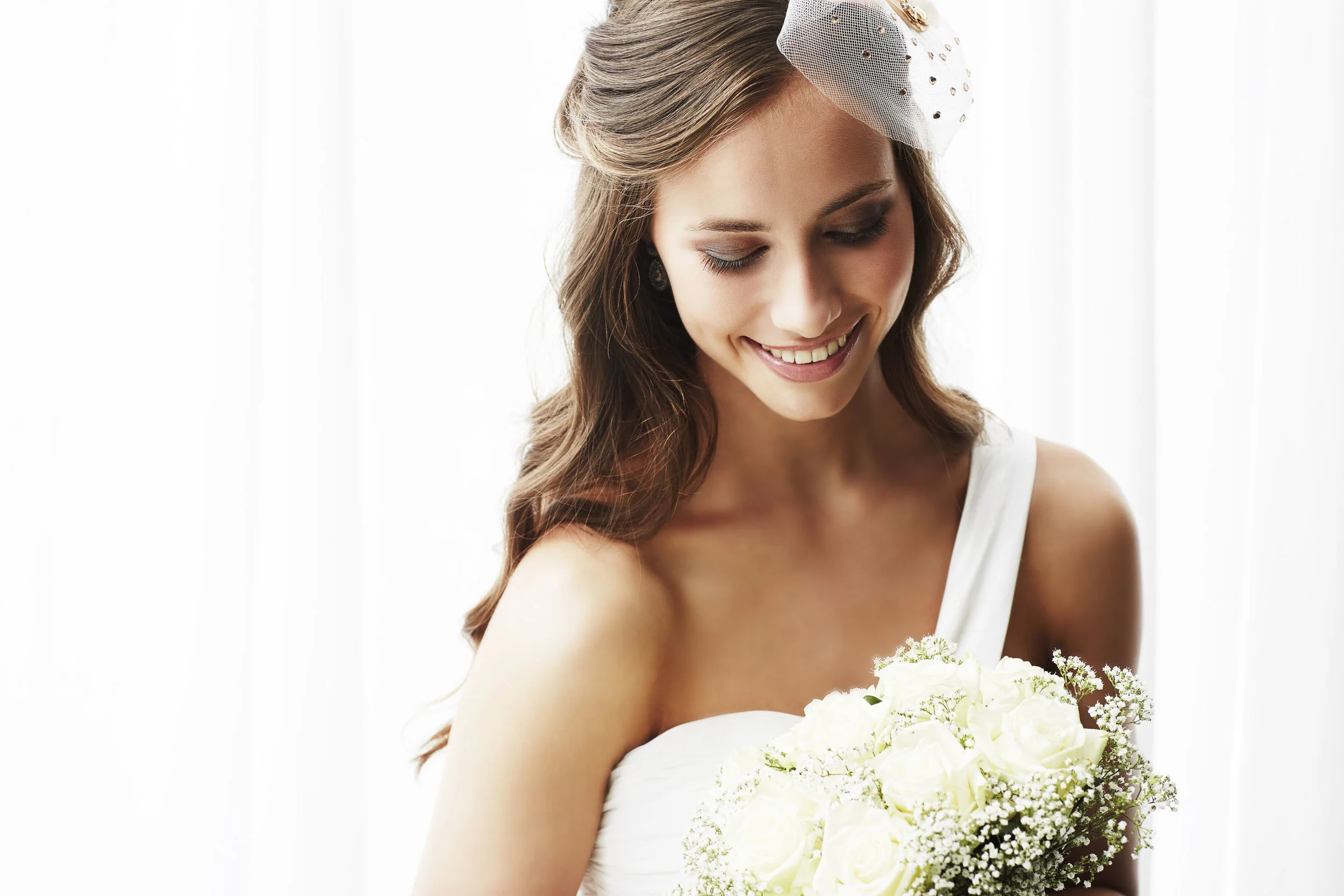 37847454 - young bride in wedding dress holding bouquet, studio shot