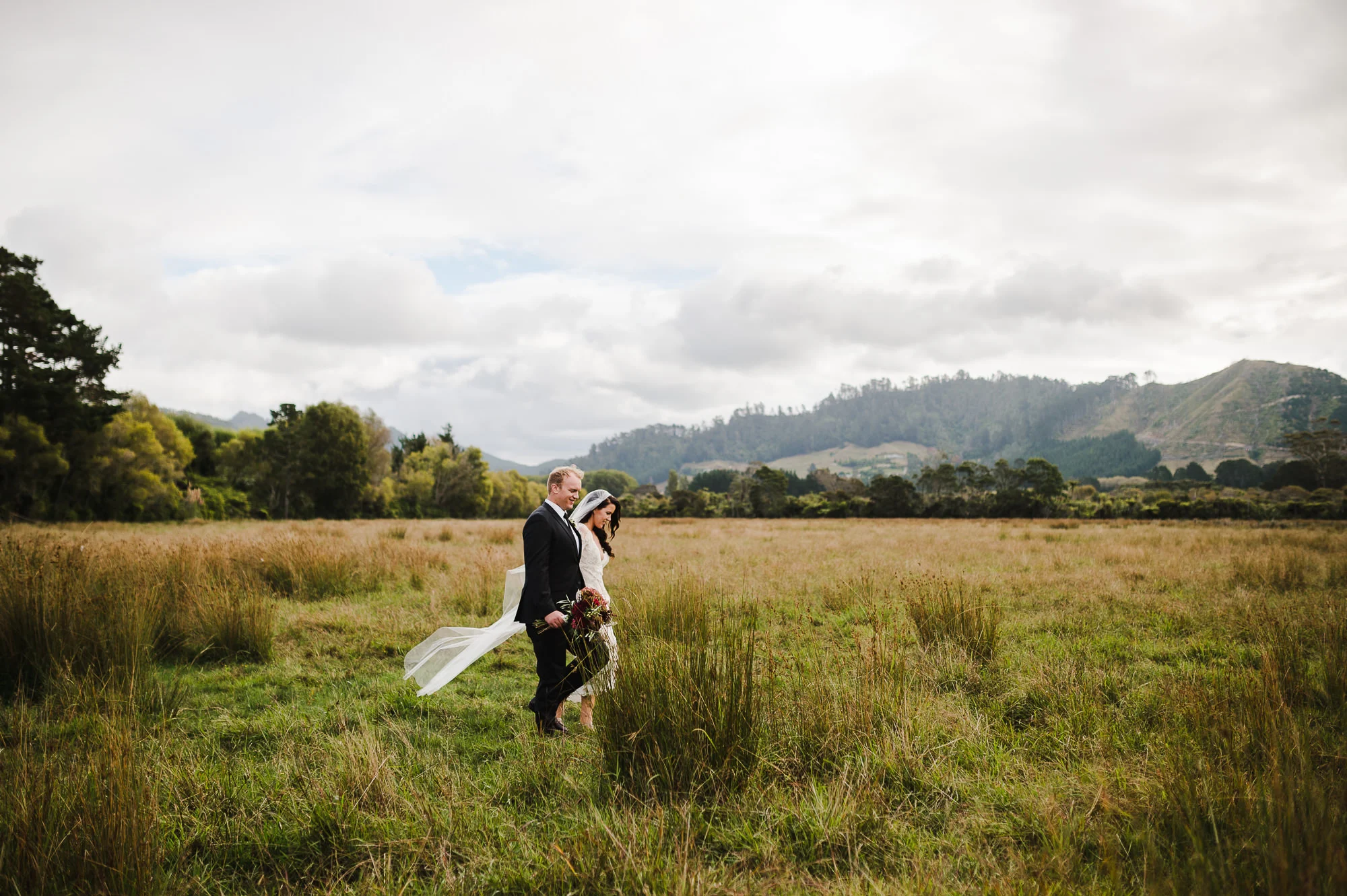wedding couple walking through field in New Zealand.jpg