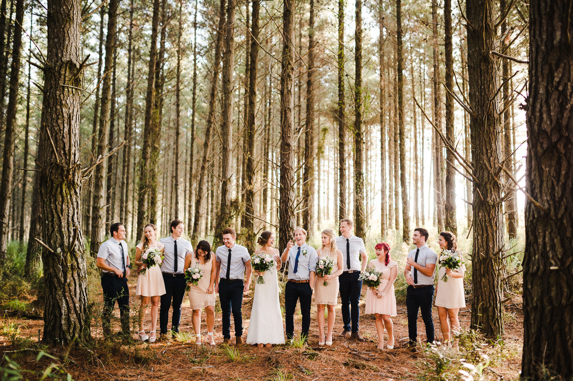 large bridal party laughing in auckland forest.jpg