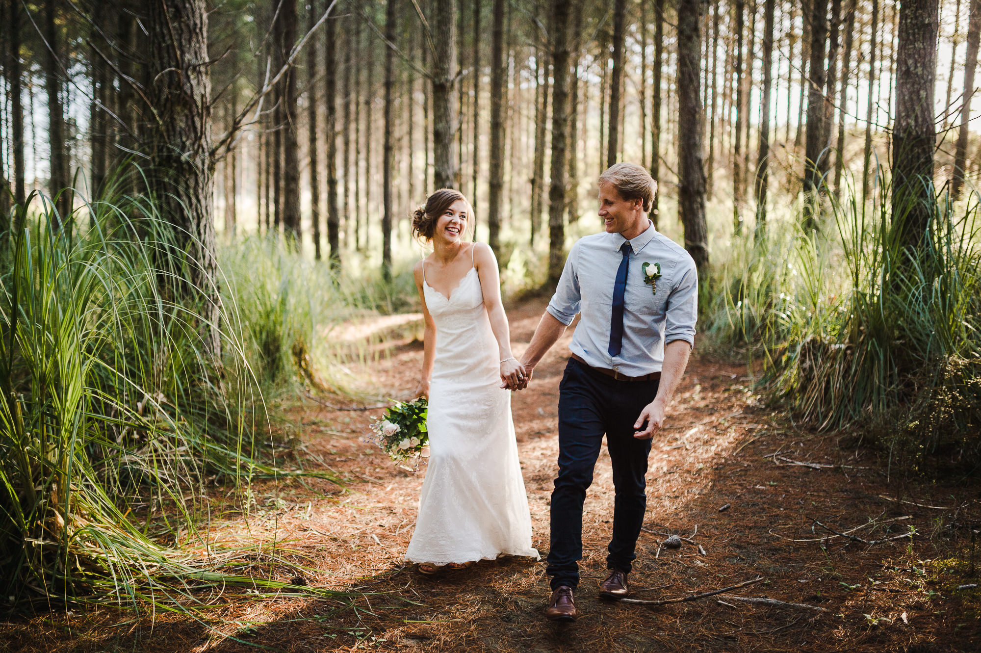 bride and groom walking through forest auckland wedding.jpg