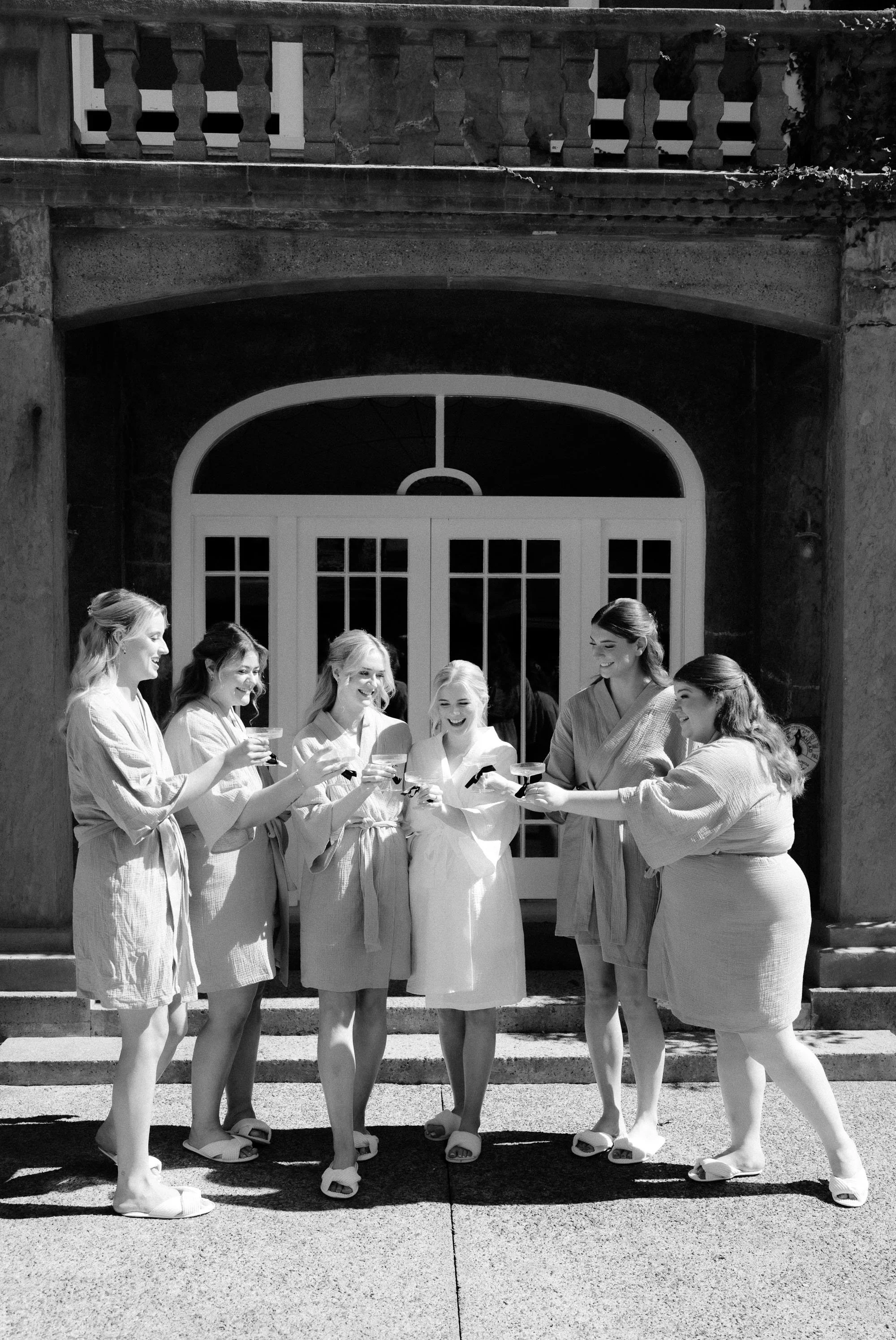 Bridesmaids cheersing champagne in matching robes at The McCallum Residence