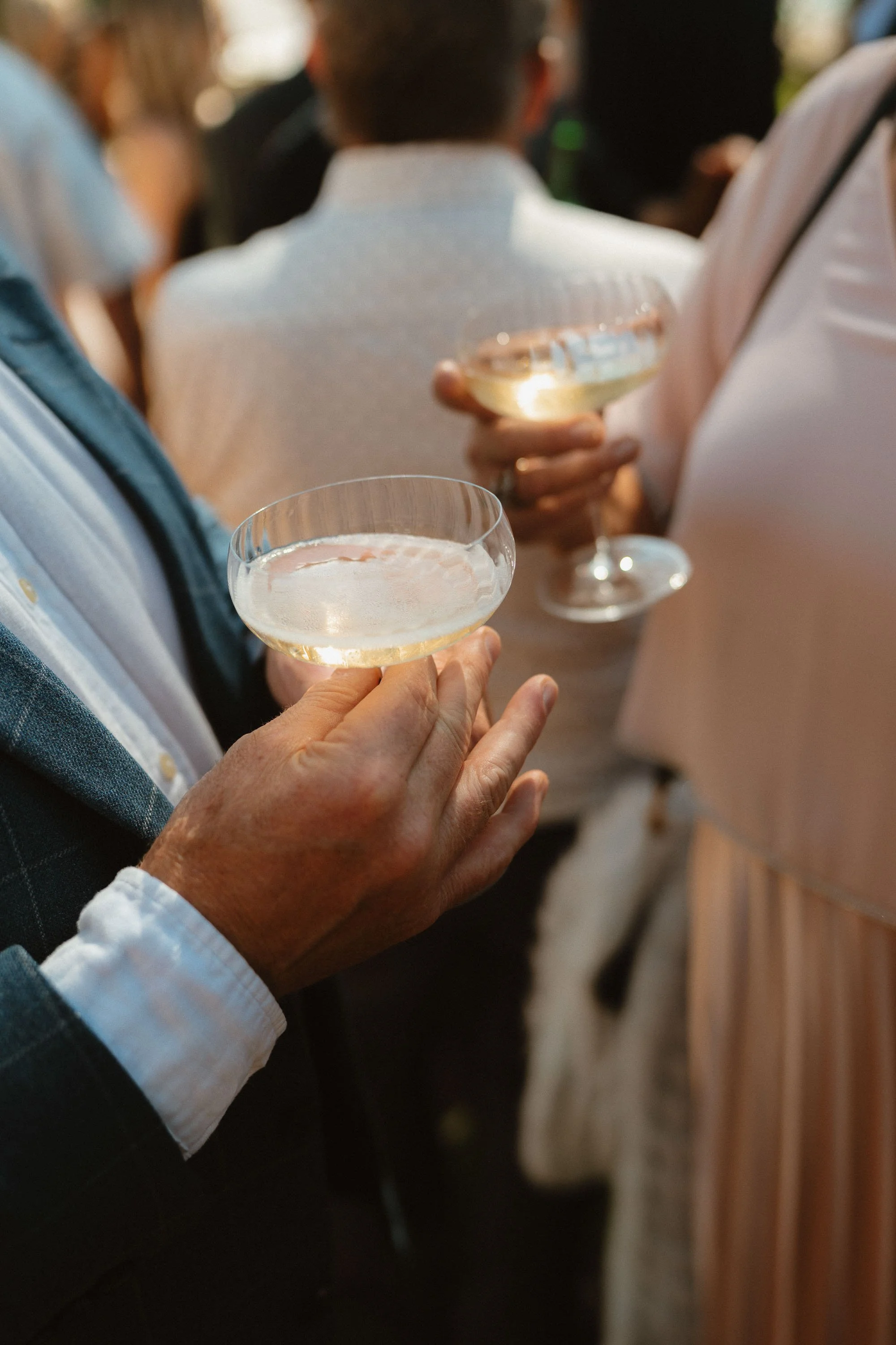 closeup of hands holding drinks at wedding