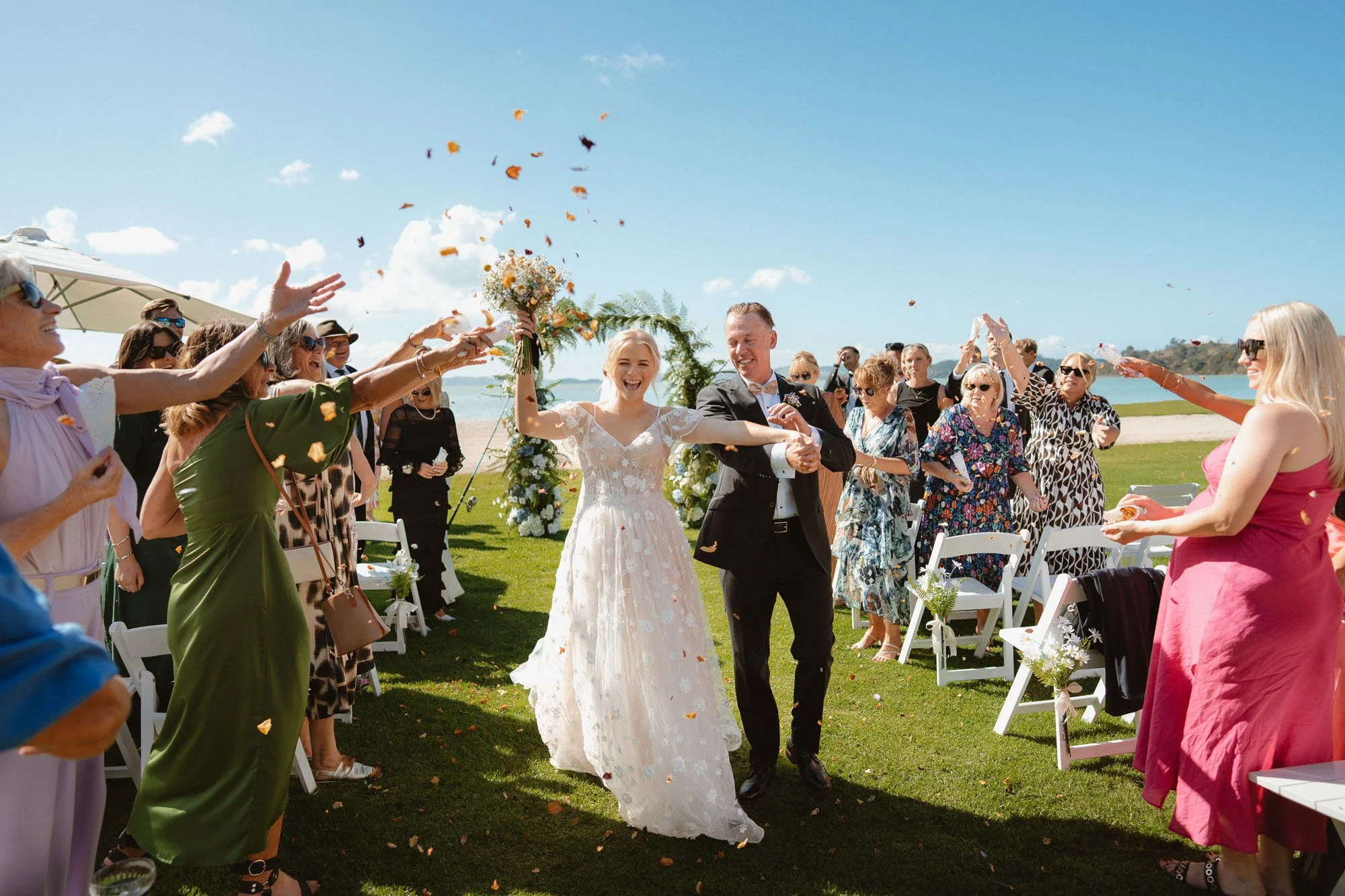 Happy couple walking down aisle with confetti at The McCallum Residence