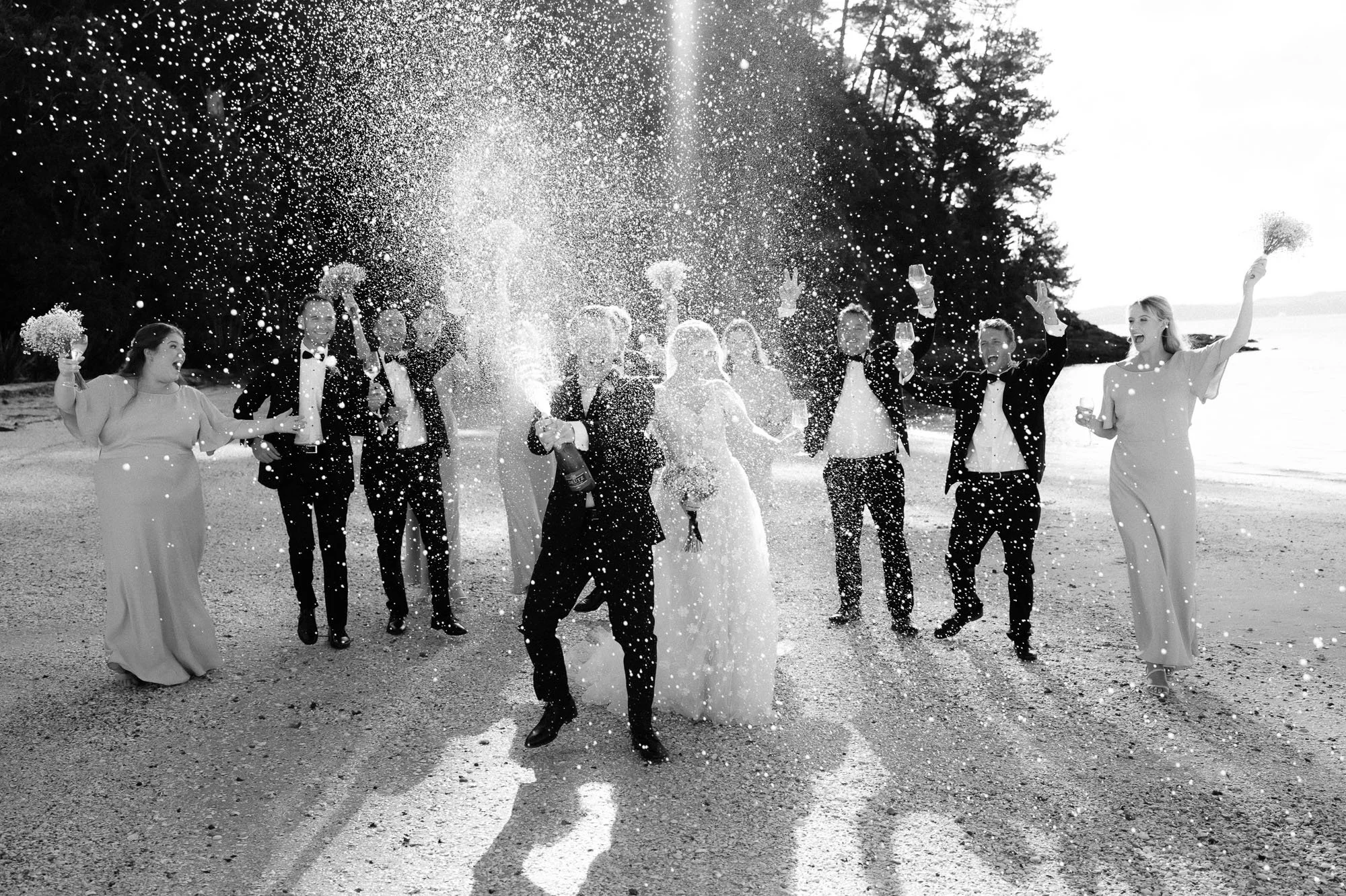Black and white image of bridal party spraying champagne