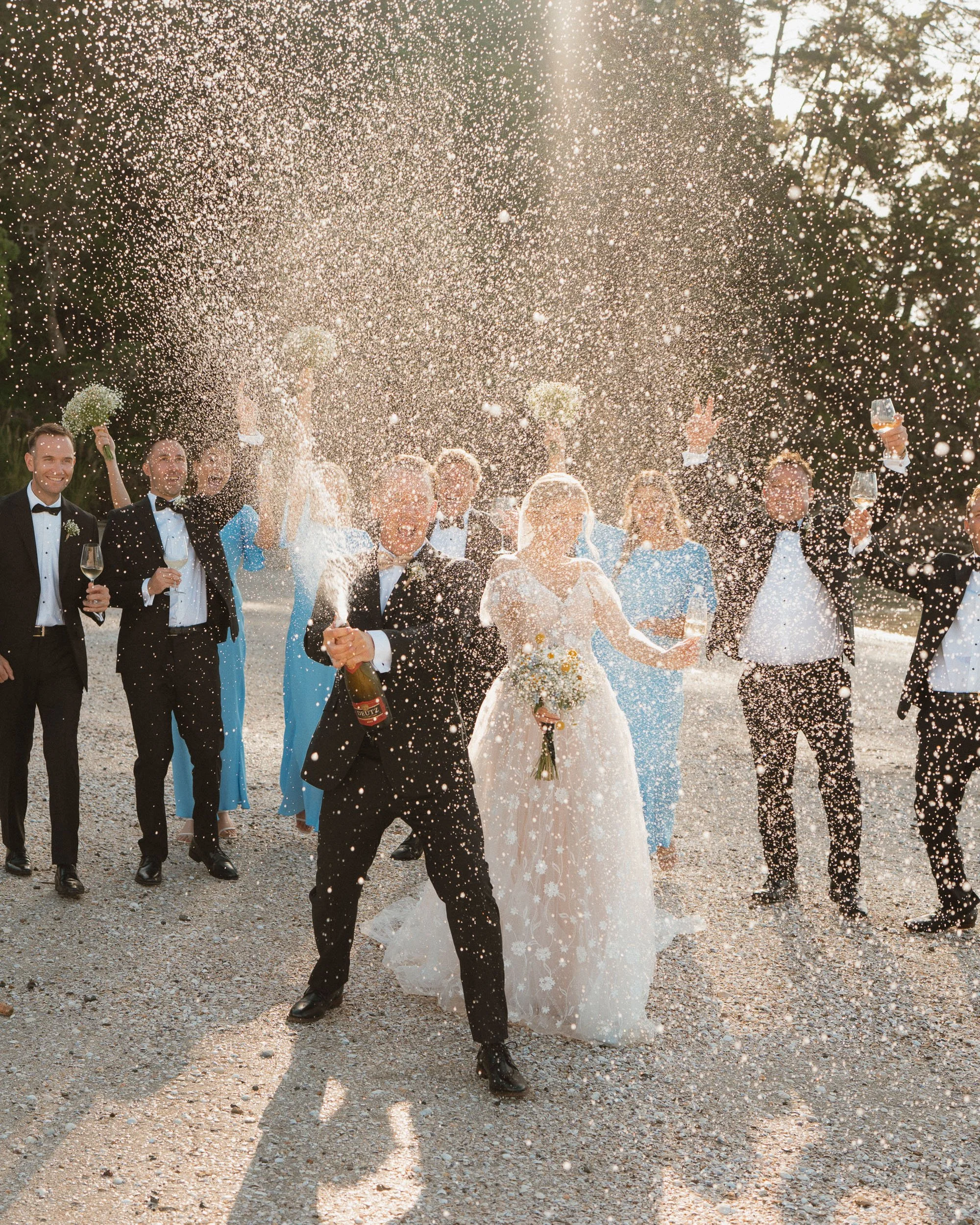Bridal party champagne spray shot at The McCallum Residence backlit on the beach