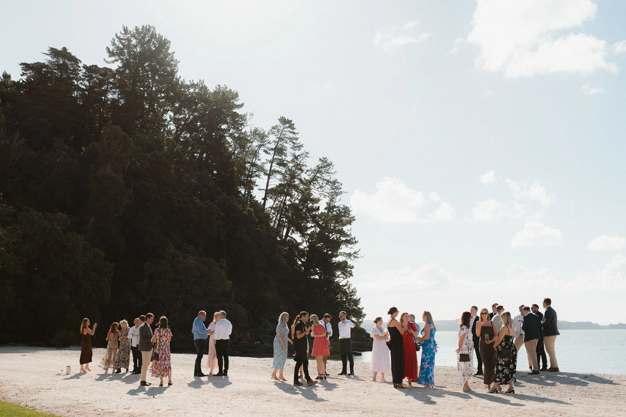 Guests mingling on white shell beach at The McCallum Residence