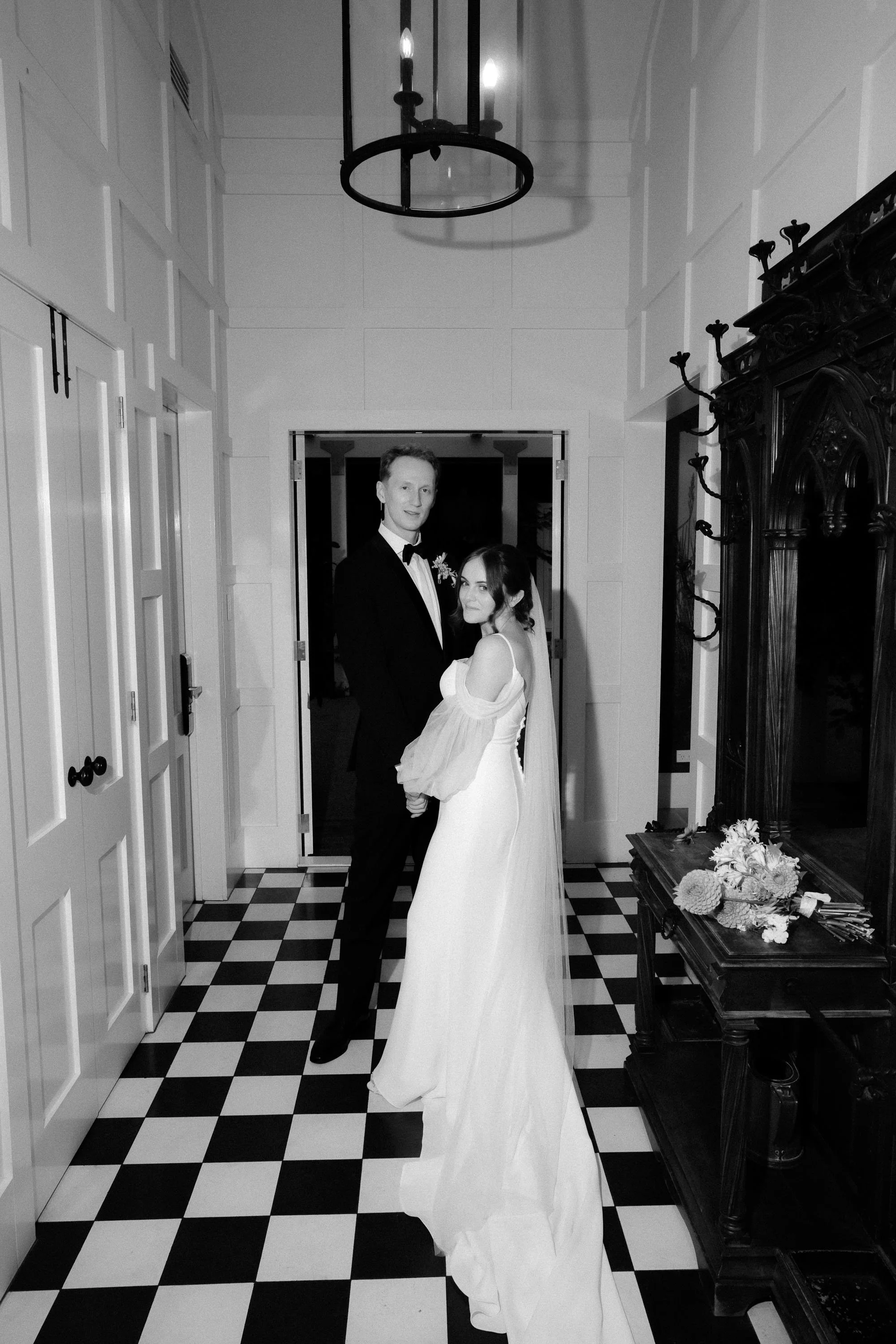 editorial style flash portrait of bride and groom at mudbrick on black and white tiles