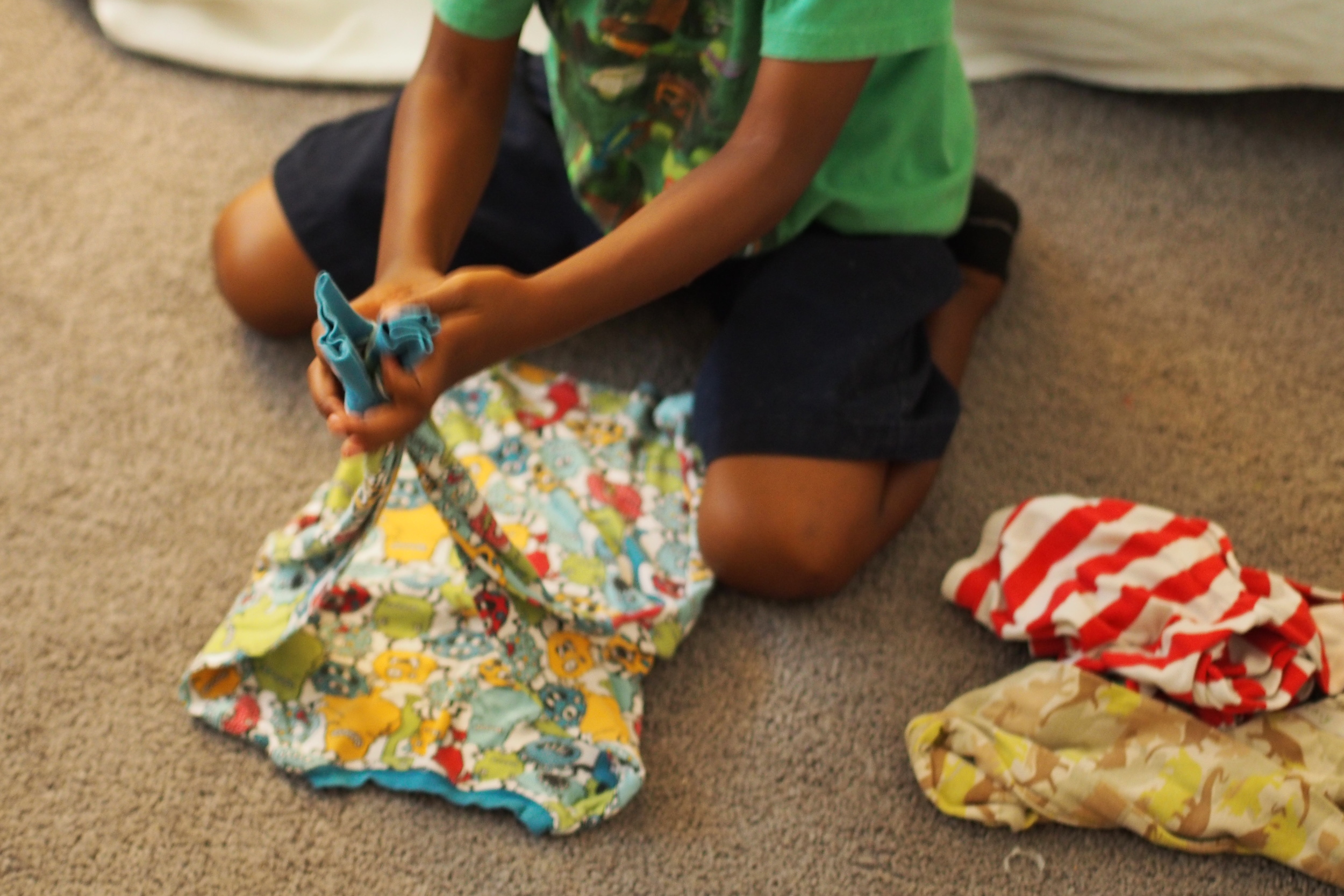 child folds clothing 