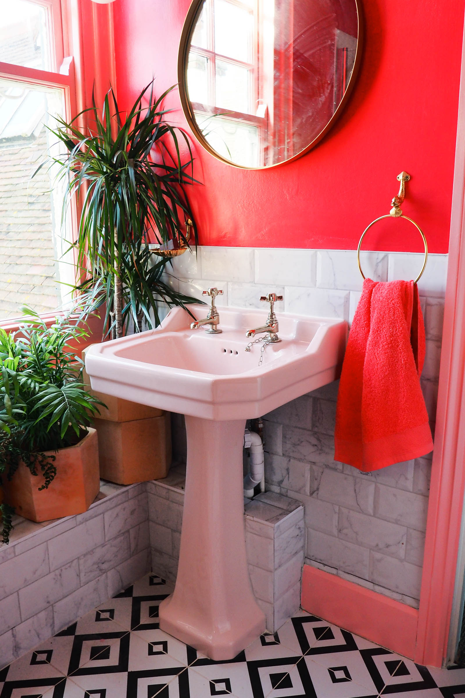 Amy's pink and marble bathroom with black and white tiles, green houseplants and brass accents.