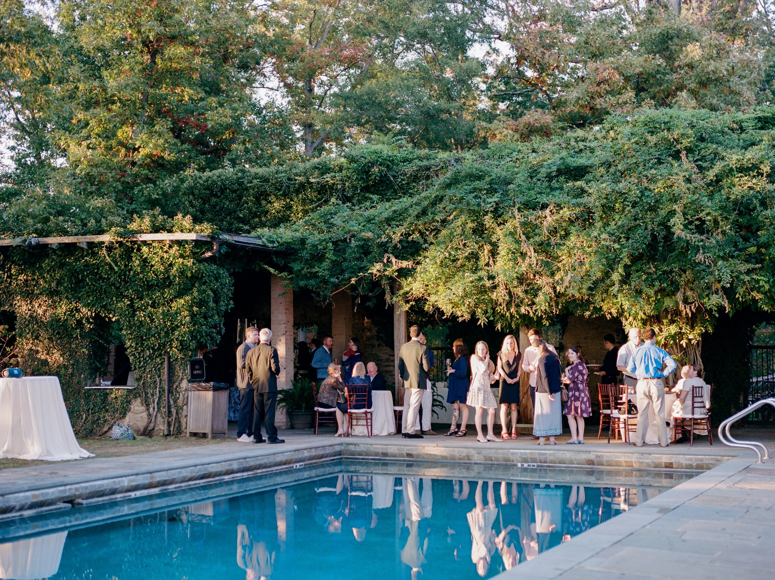 Wedding guests mingling during cocktail hour on the pool terrace at Goodstone Inn