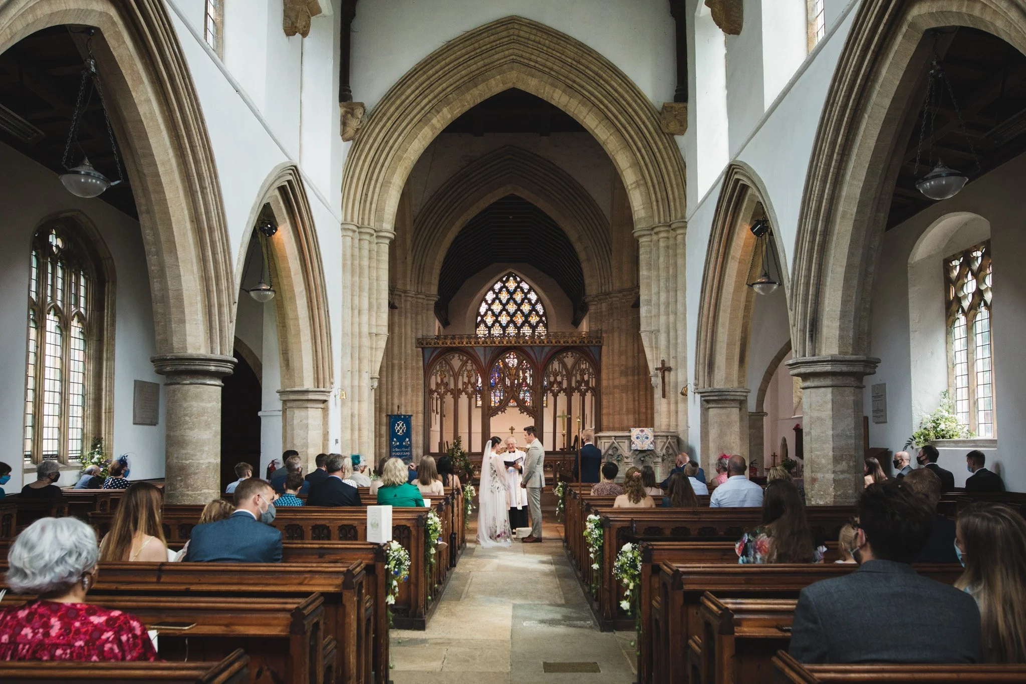 A view of the church ceremony from the back of St Mary's in Felmersham, Bedfordshire. The bride and groom face each other as they say their vows.