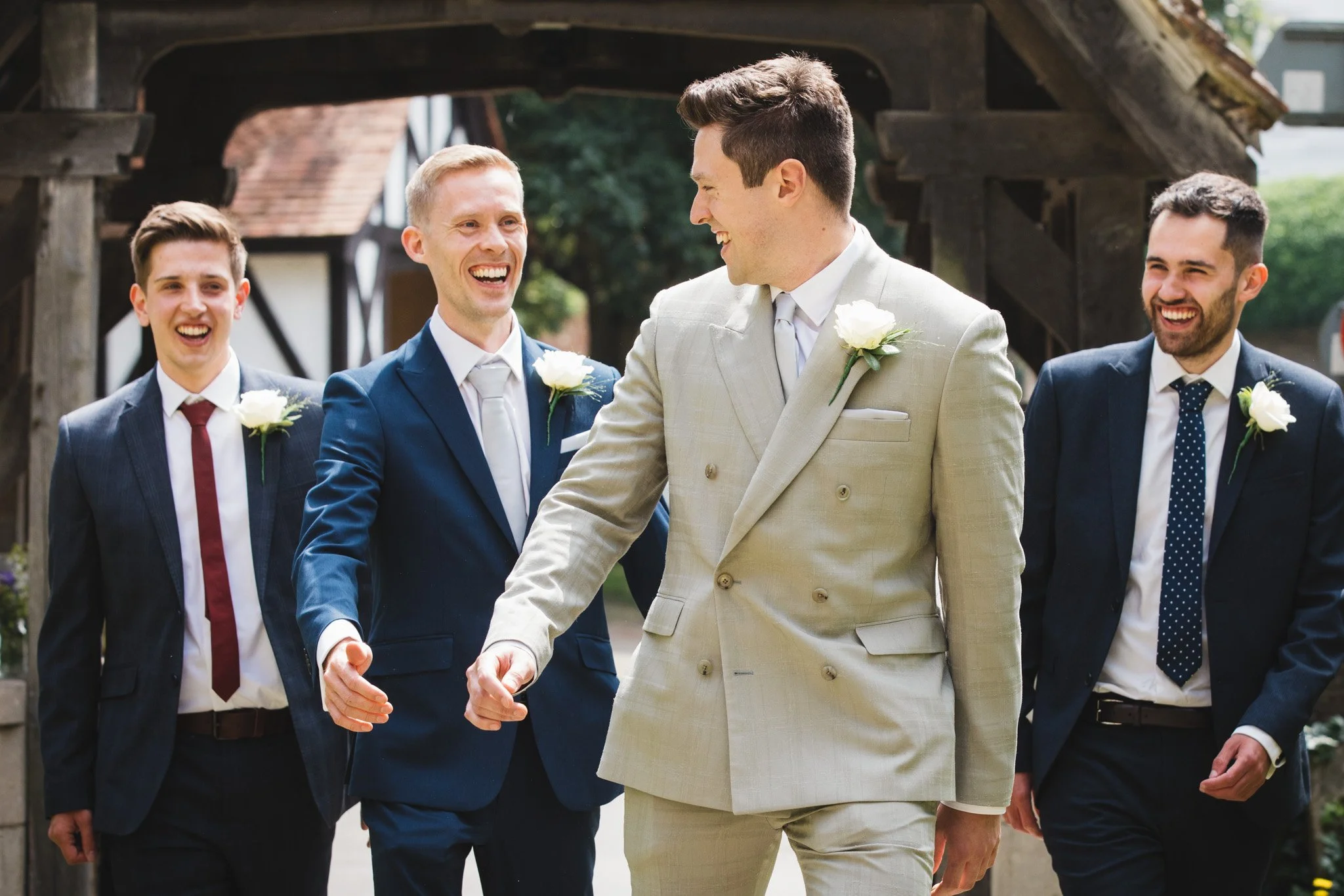 The groom and his groomsmen laugh together as they walk to the church.