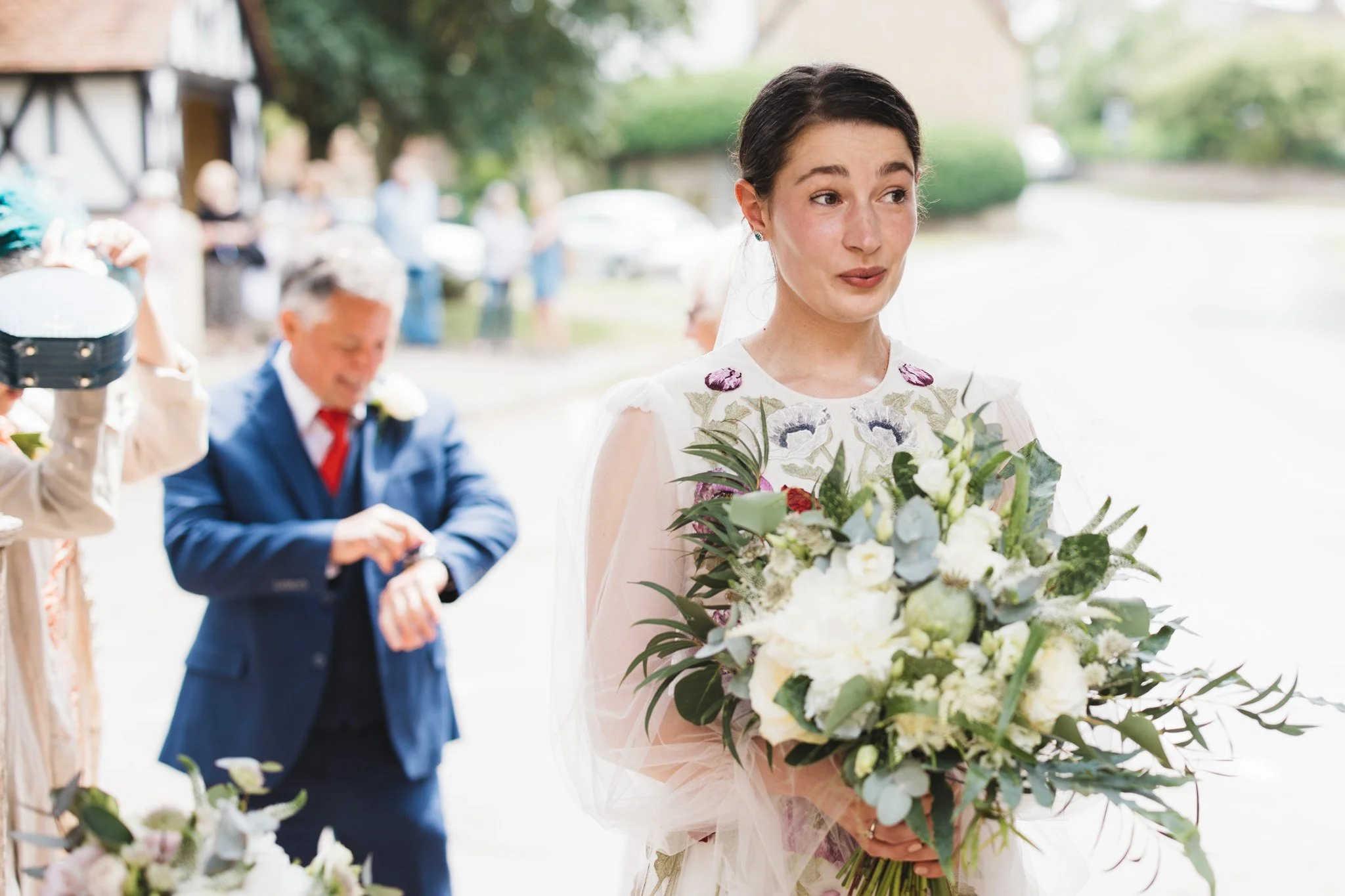 The bride takes a grounding breath before the ceremony. Her dad is in the background checking the time on his watch.