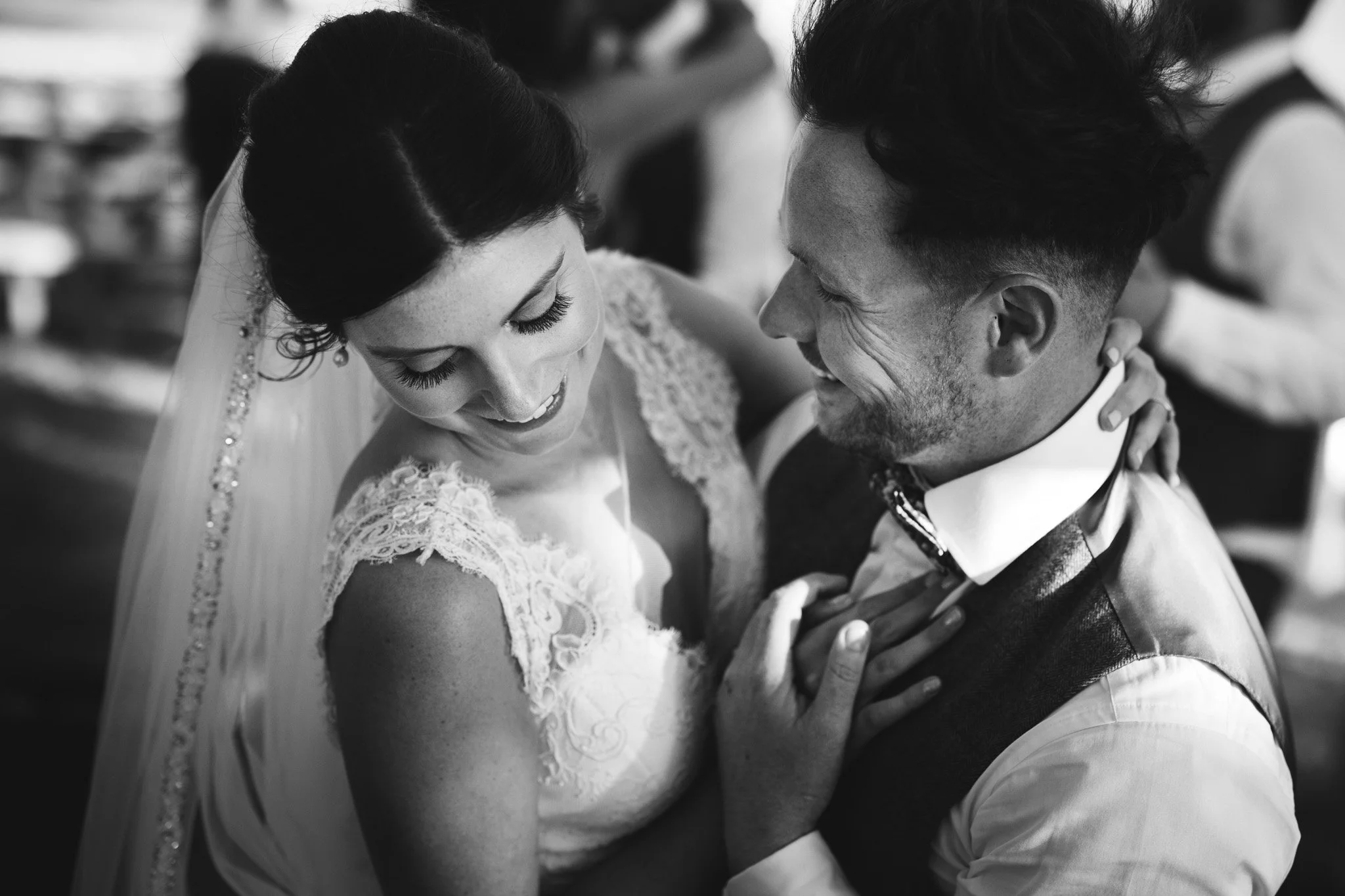 The bride and groom smile during their first dance, with her hand on his chest.