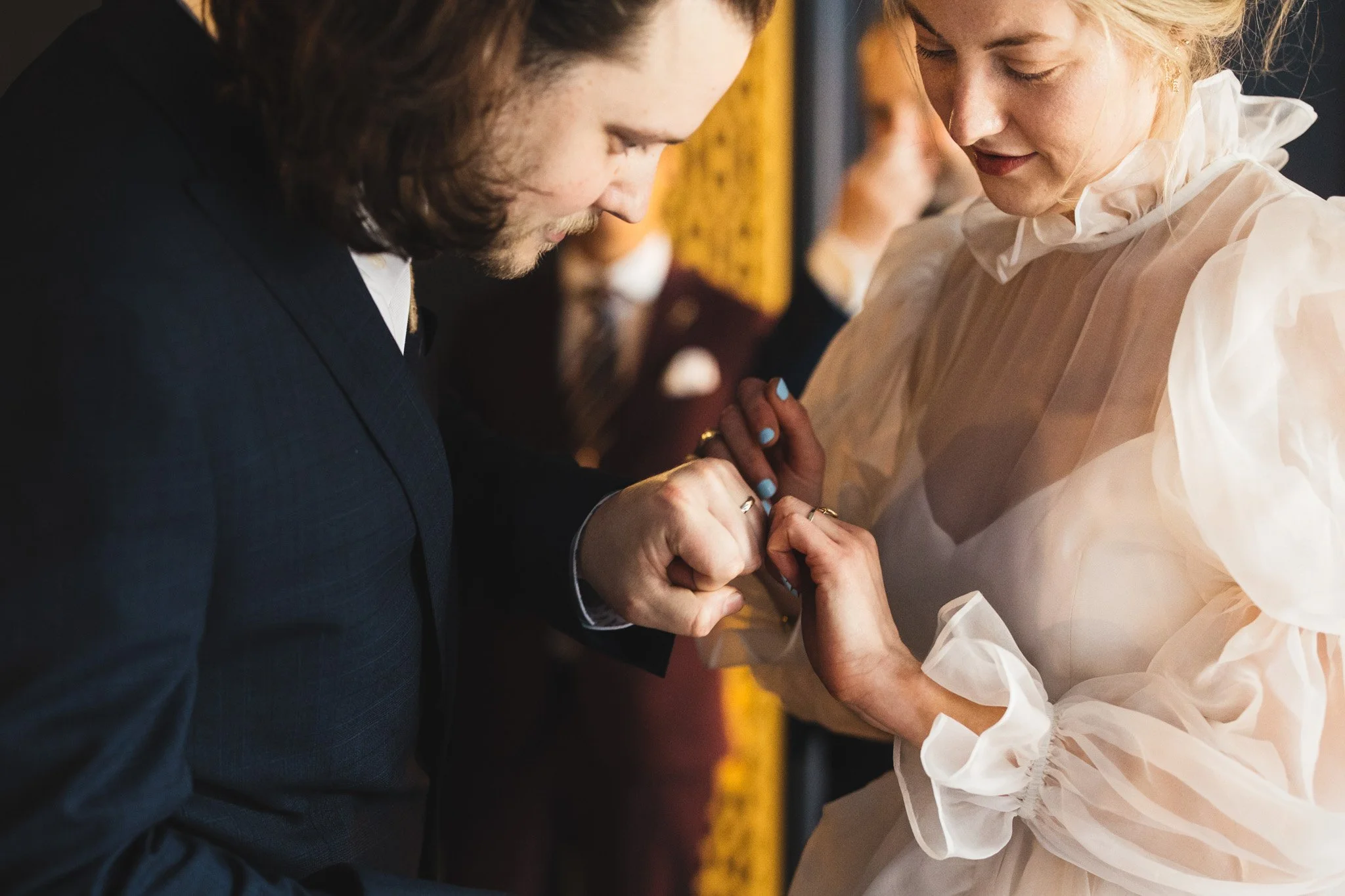 A close up of the bride and groom looking at their new wedding rings.