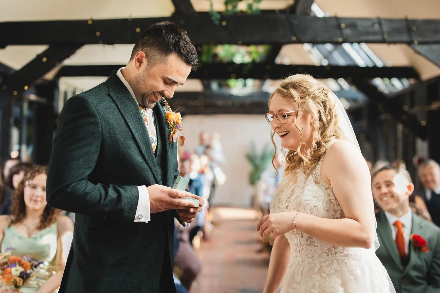 A couple smile as they exchange rings in the Old Dairy at South Farm.