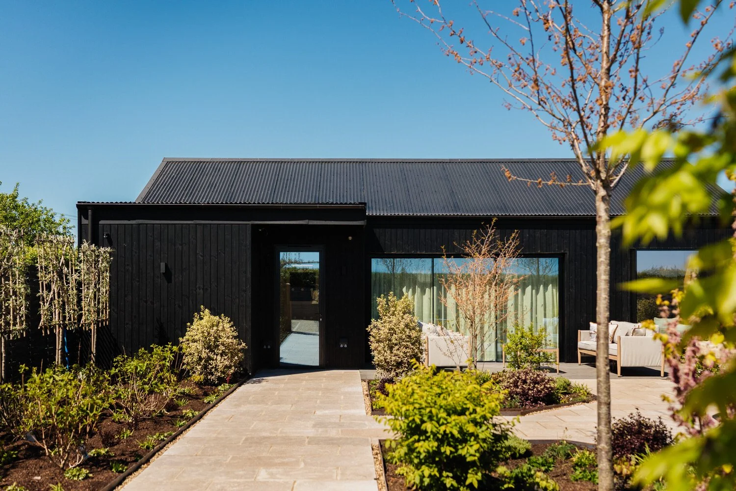 An exterior view of South Farm's Apple Shed. The sky is bright blue and there is greenery in the foreground.