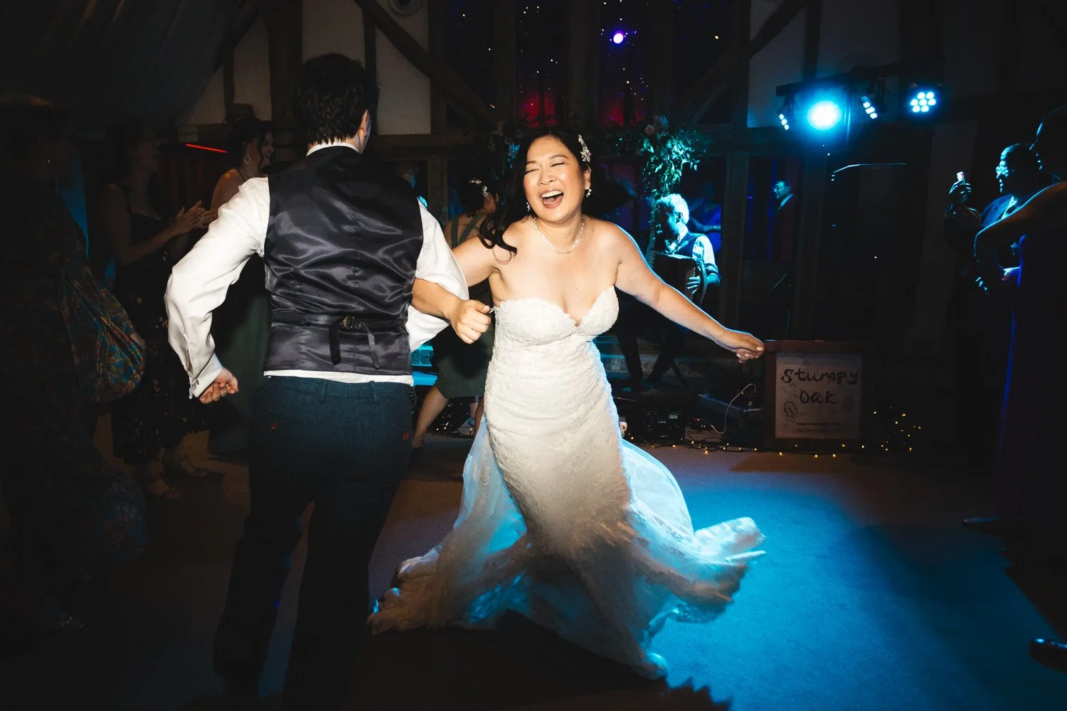 The bride laughs as she is flung around during ceilidh dancing with her groom.