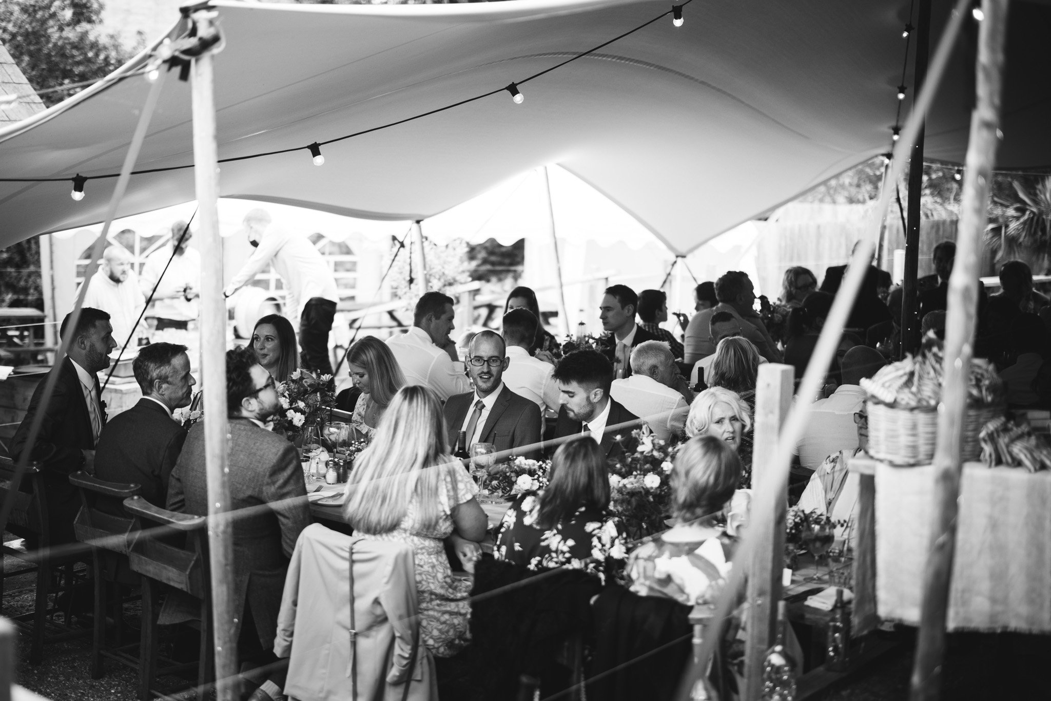 A black and white shot of guests chatting during the wedding breakfast.