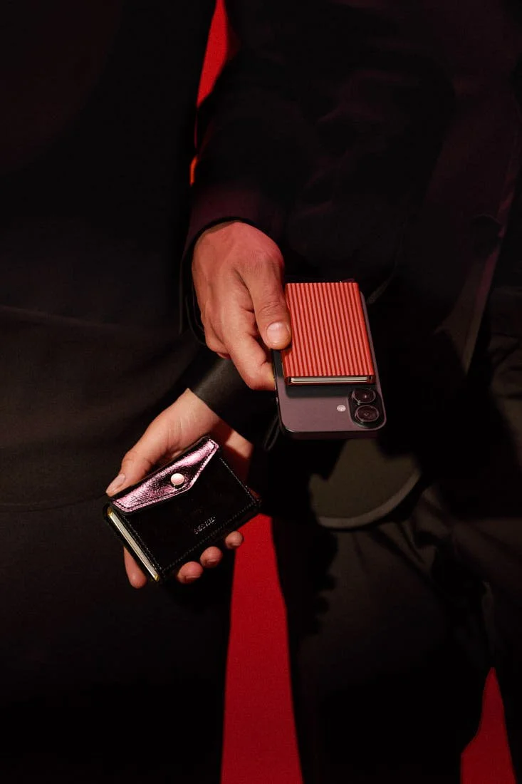 SECRID Premium Envelope Wallet+ Naplak in black and Premium Cardprotector+ Fluted for MagSafe in red, held together with a smartphone against a dark red and black setting, LE MILE Magazine.