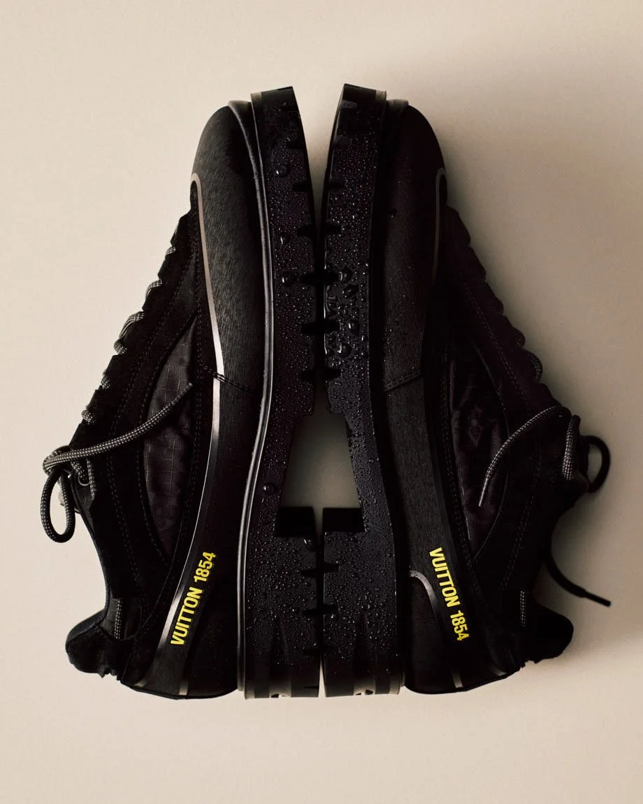 Pair of black Louis Vuitton lace-up shoes positioned to show their thick lugged soles and yellow details.