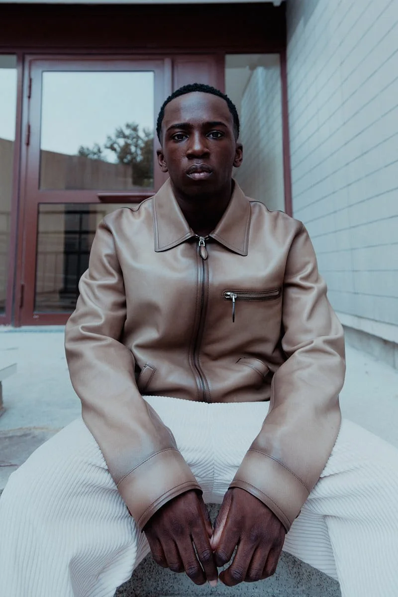 ARALOYIN OSHUNREMI for LE MILE Magazine Araloyin wears a leather jacket, cream trousers and black-and-brown shoes by BERLUTI