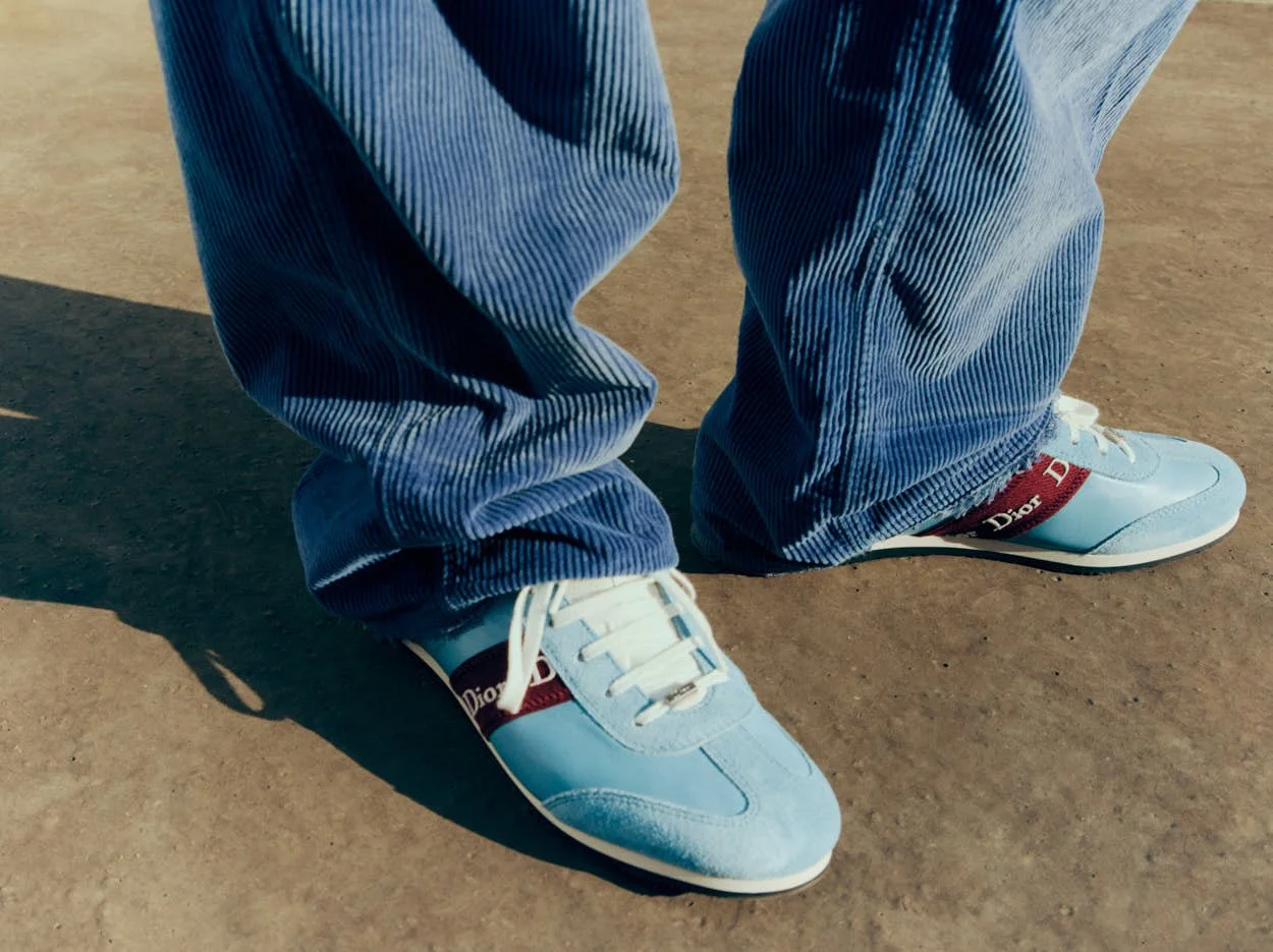 Pale blue Dior Ribbon sneakers with burgundy Dior bands on green tiles.