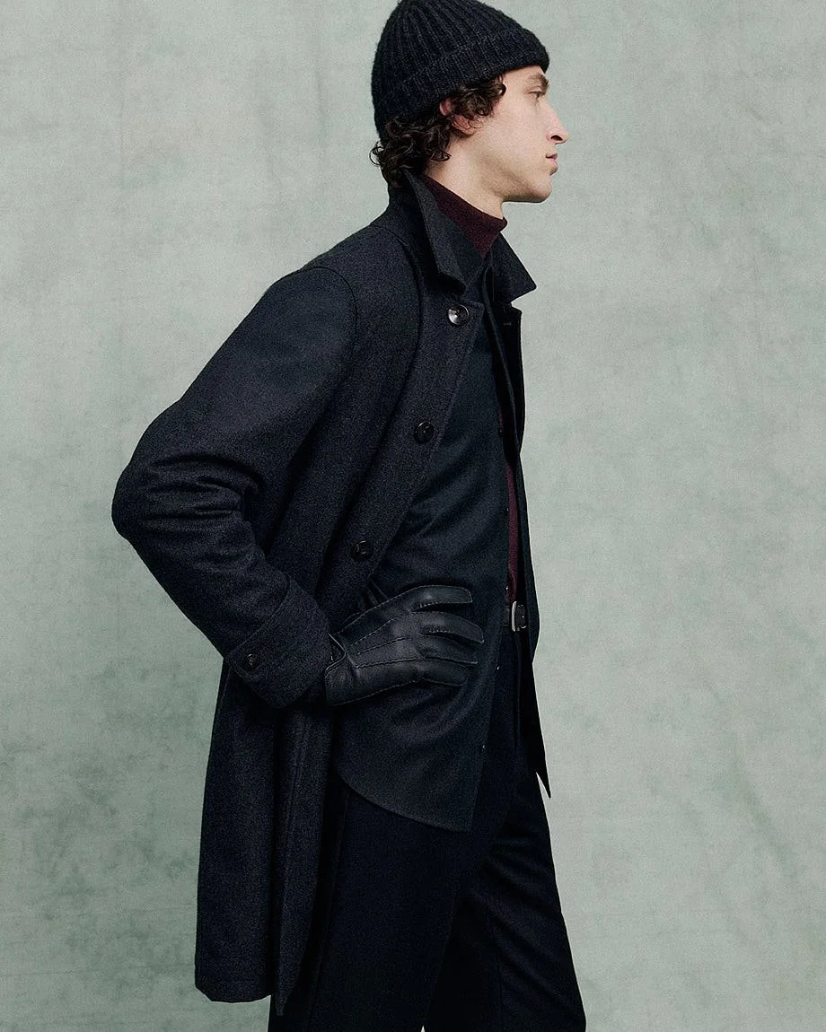 AGNONA Autumn/Winter 2026 menswear look with long dark coat, knit beanie, gloves and layered tailoring, LE MILE Magazine.