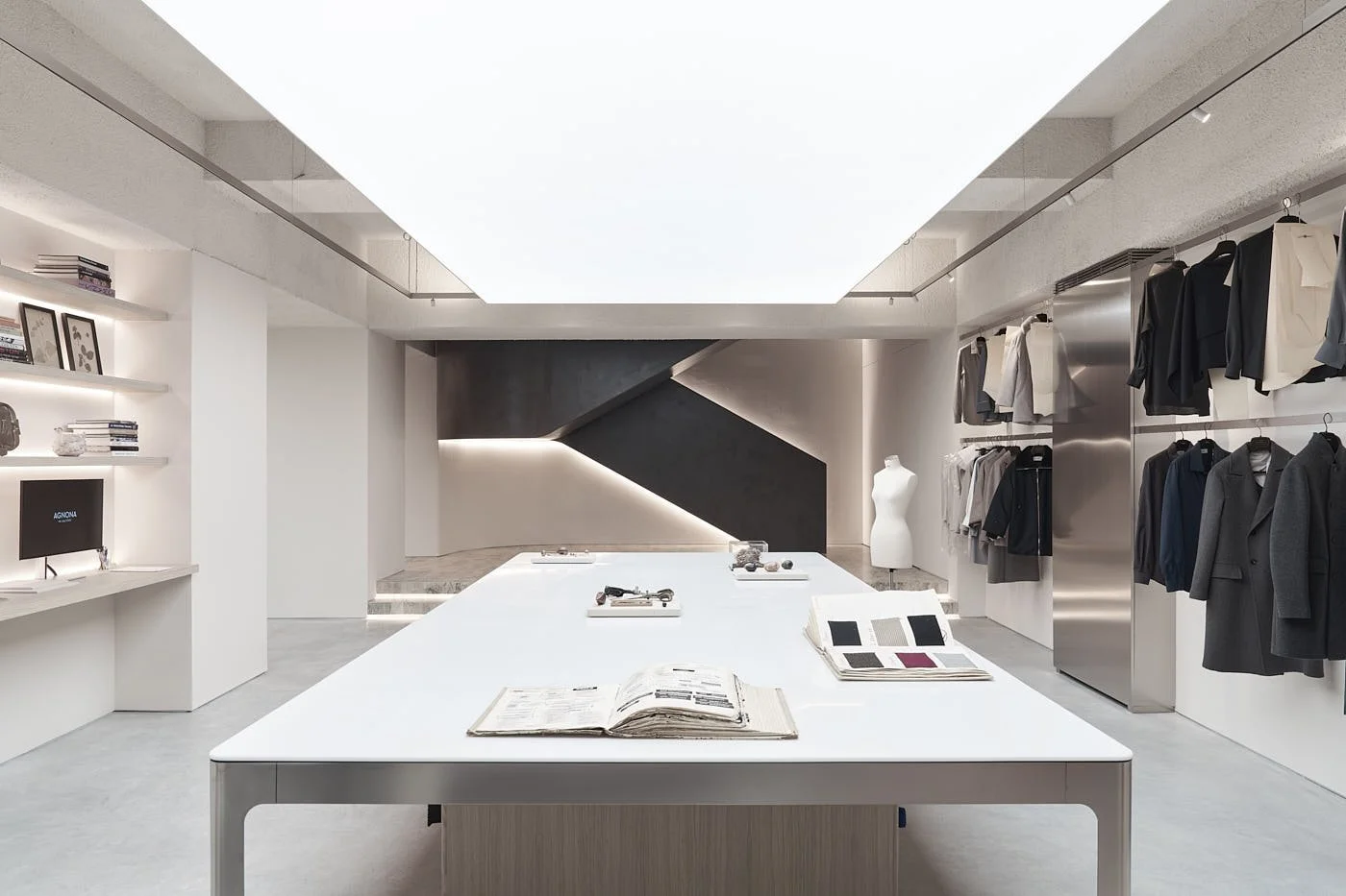 AGNONA showroom at Via Archimede 53 in Milan with garments, fabric books and textile archives around a central worktable, LE MILE Magazine.
