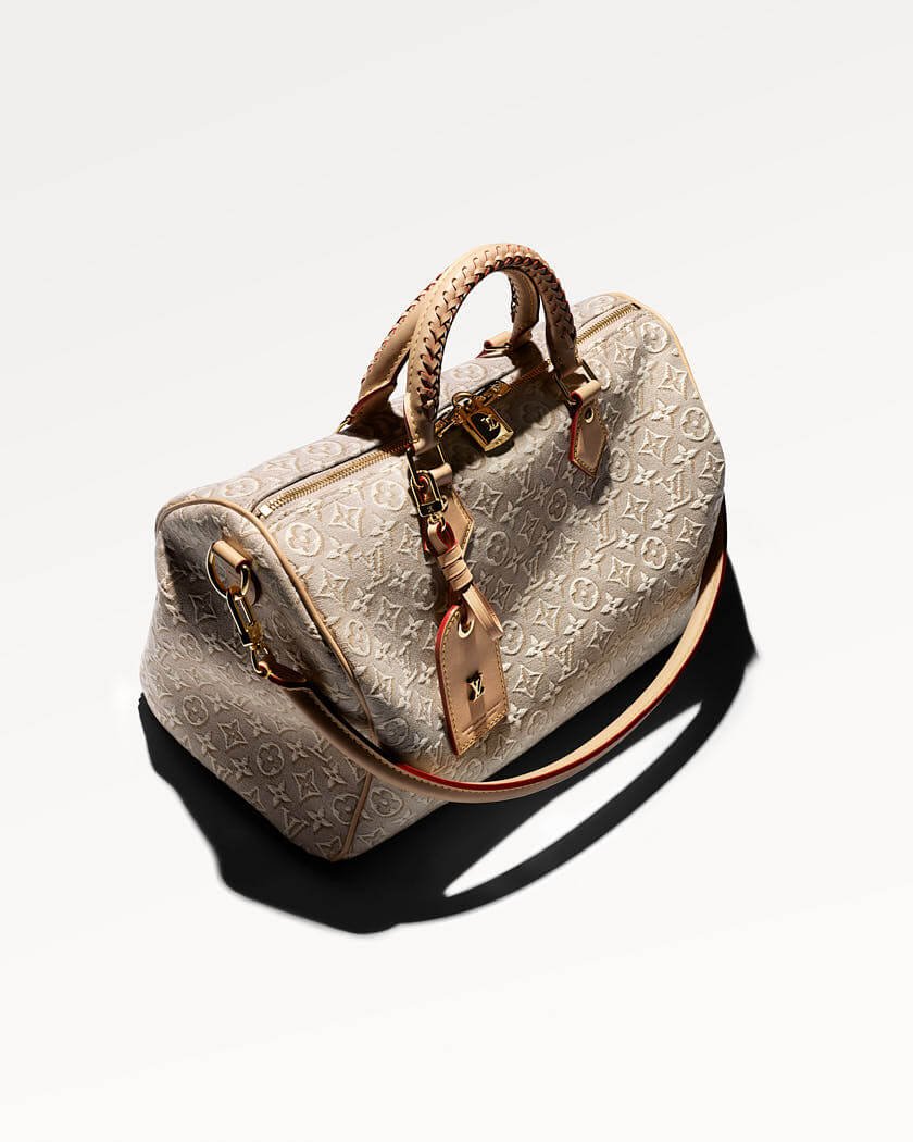 Louis Vuitton Speedy 30 Soft bag in beige Monogram Emblème Peuplier jacquard with braided top handles, natural leather trims, gold-tone hardware, luggage tag and shoulder strap on a white background