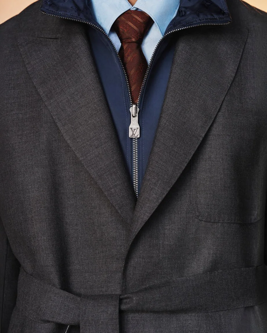 Close-up of Louis Vuitton’s belted charcoal tailoring with a blue zip collar and burgundy tie.