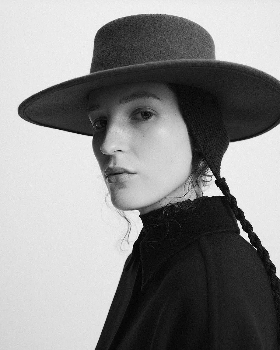 AGNONA Autumn/Winter 2026 portrait with a wide-brim hat, braided ties and dark tailored outerwear, LE MILE Magazine.