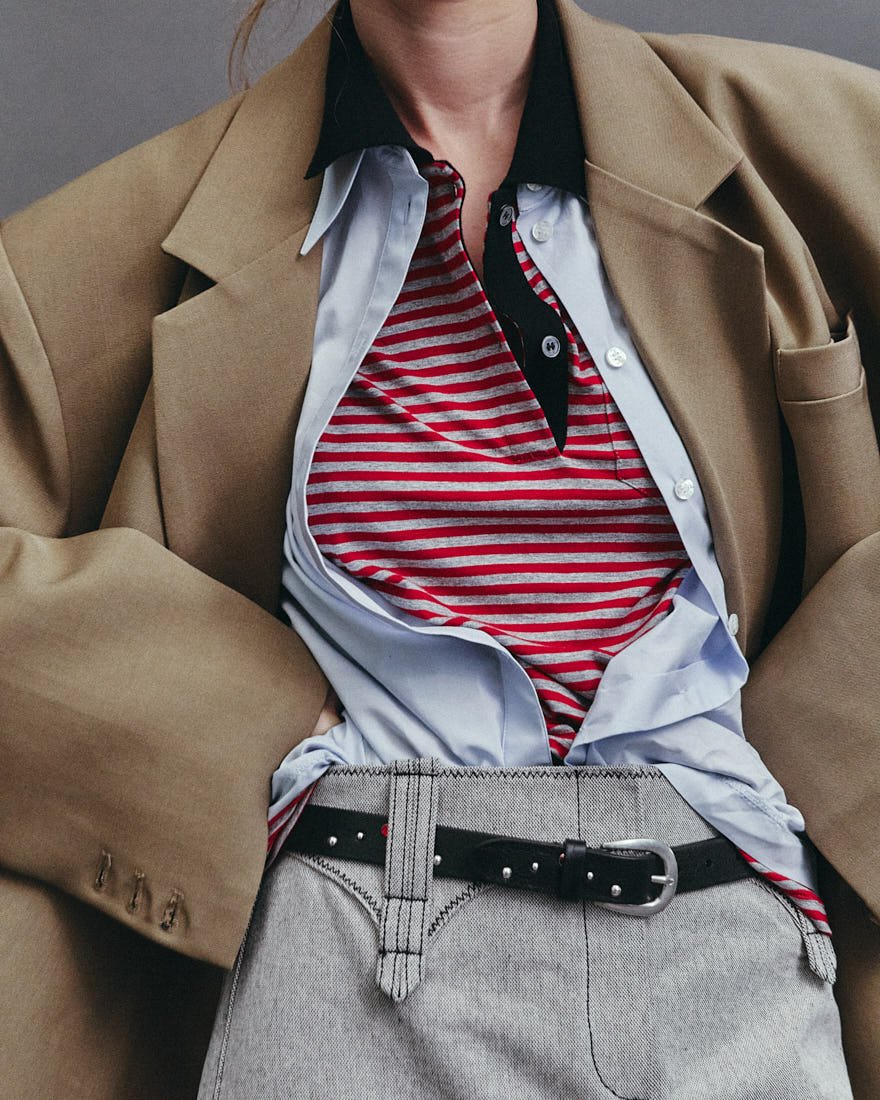 KIRA ALFERINK for LE MILE Magazine Digital Fashion Editorial SS26 photo by Antonio Crotti Kira wears blazer by THE FRANKIE SHOP, shirt and denim skirt by TORY BURCH, t-shirt and tartan skirt by N21 and belt by PAUL SMITH