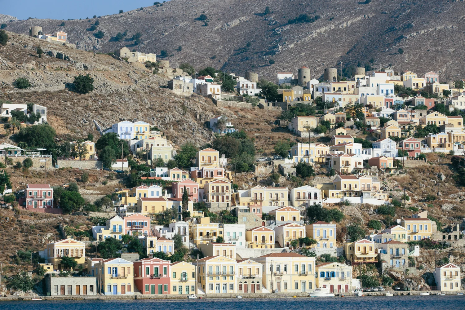 Casas coloridas em um bairro de encosta ao longo do mar, com morros ao fundo