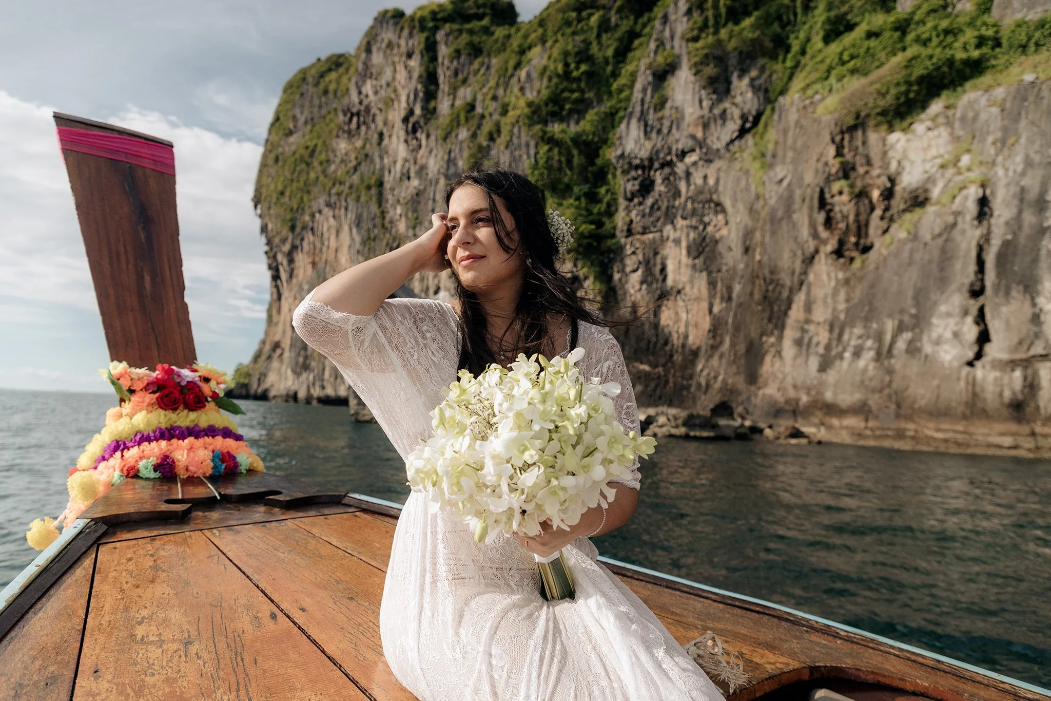 Uma noiva sentada num barco, segurando o seu bouquet, com um cenário de águas serenas.