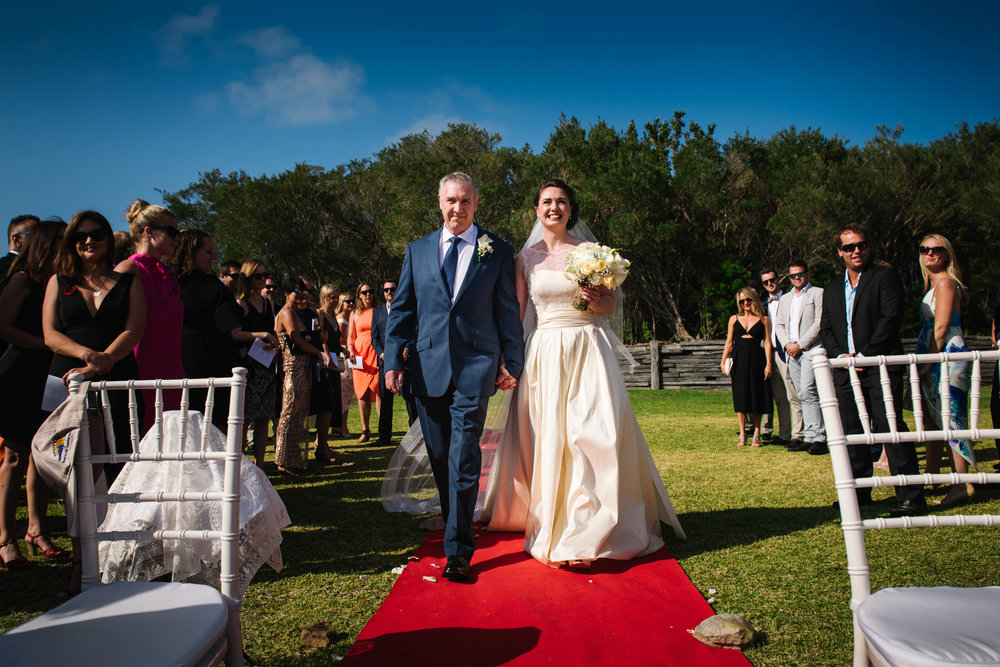 Father and bride walk down red aisle