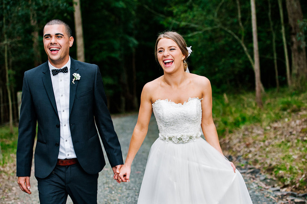 A newlywed couple walk along the entrance to Greenfield Farm Estate