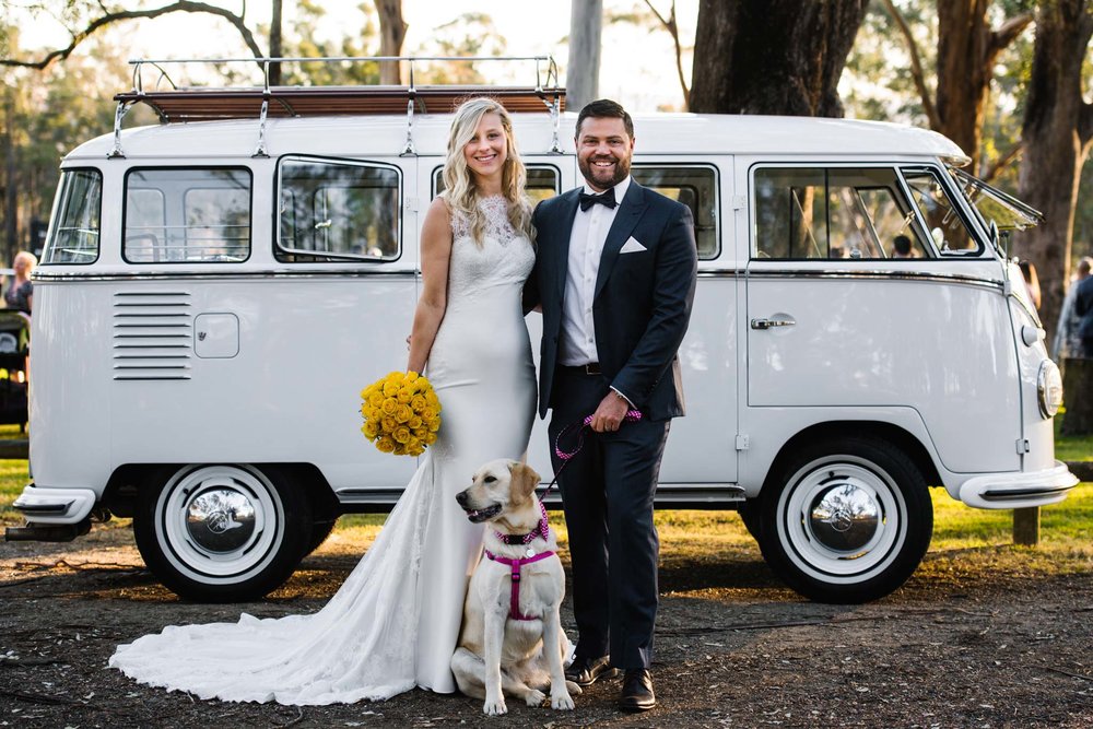 Bride, groom and yellow lab in front of white combi van