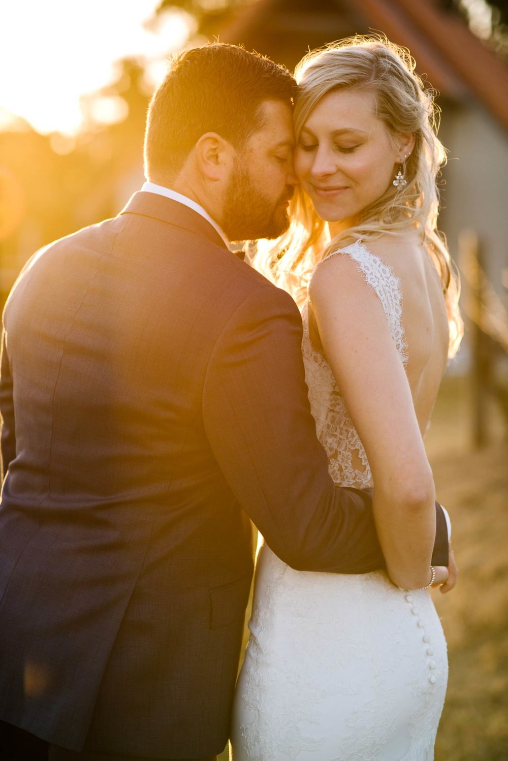 Backlit portrait of bride and groom with eyes closed
