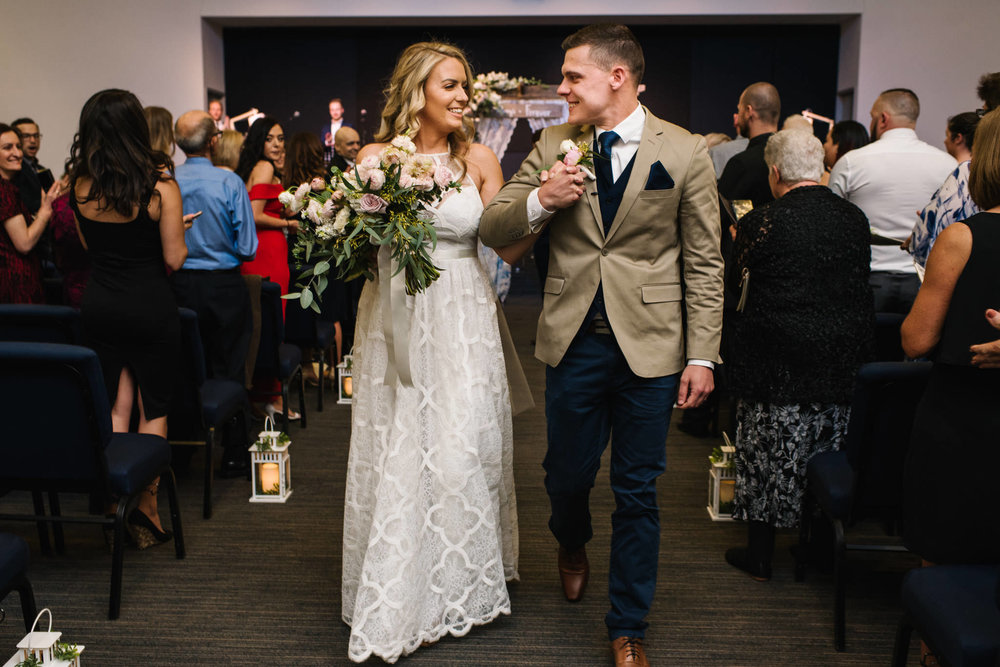 Bride and groom smiling at each other as exit the wedding ceremony