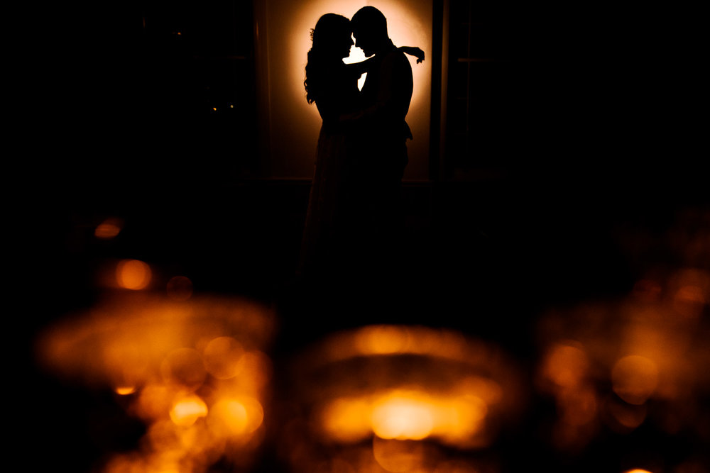 Bride and groom embrace amongst candlelight at wedding reception