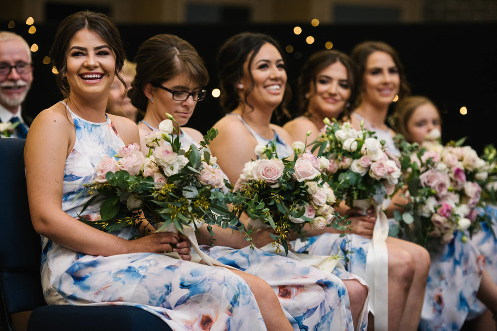 Happy bridesmaids in floral gowns during wedding ceremony