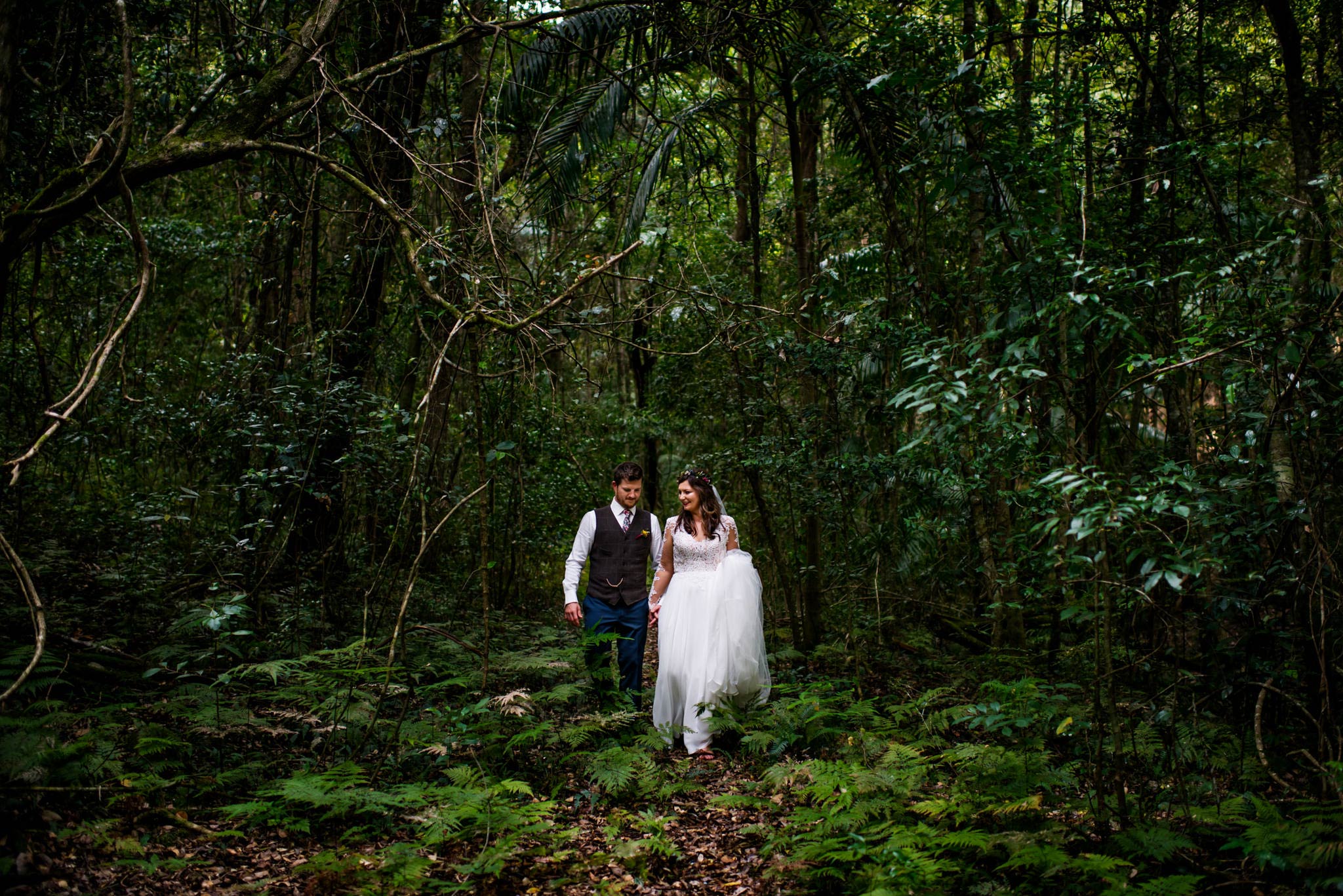 Bride and groom walk through rainforest at country wedding NSW