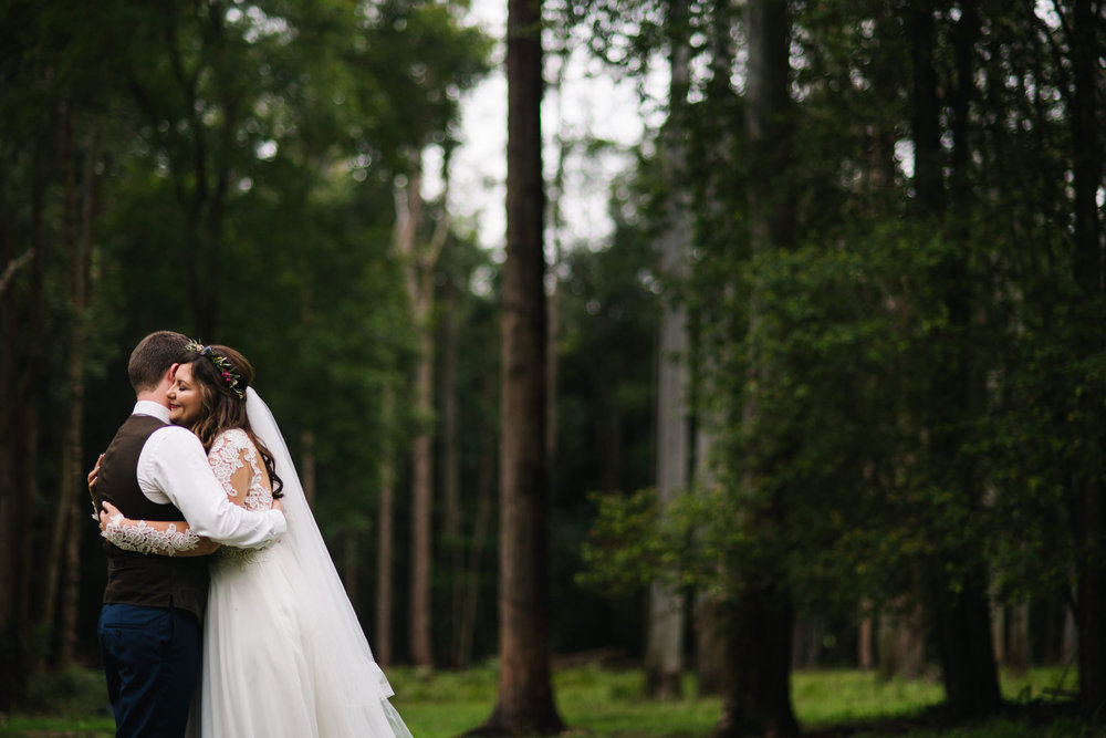 Bride and groom embrace in the woods 