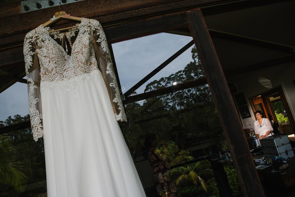 Vintage dress hanging with bride getting ready in the background