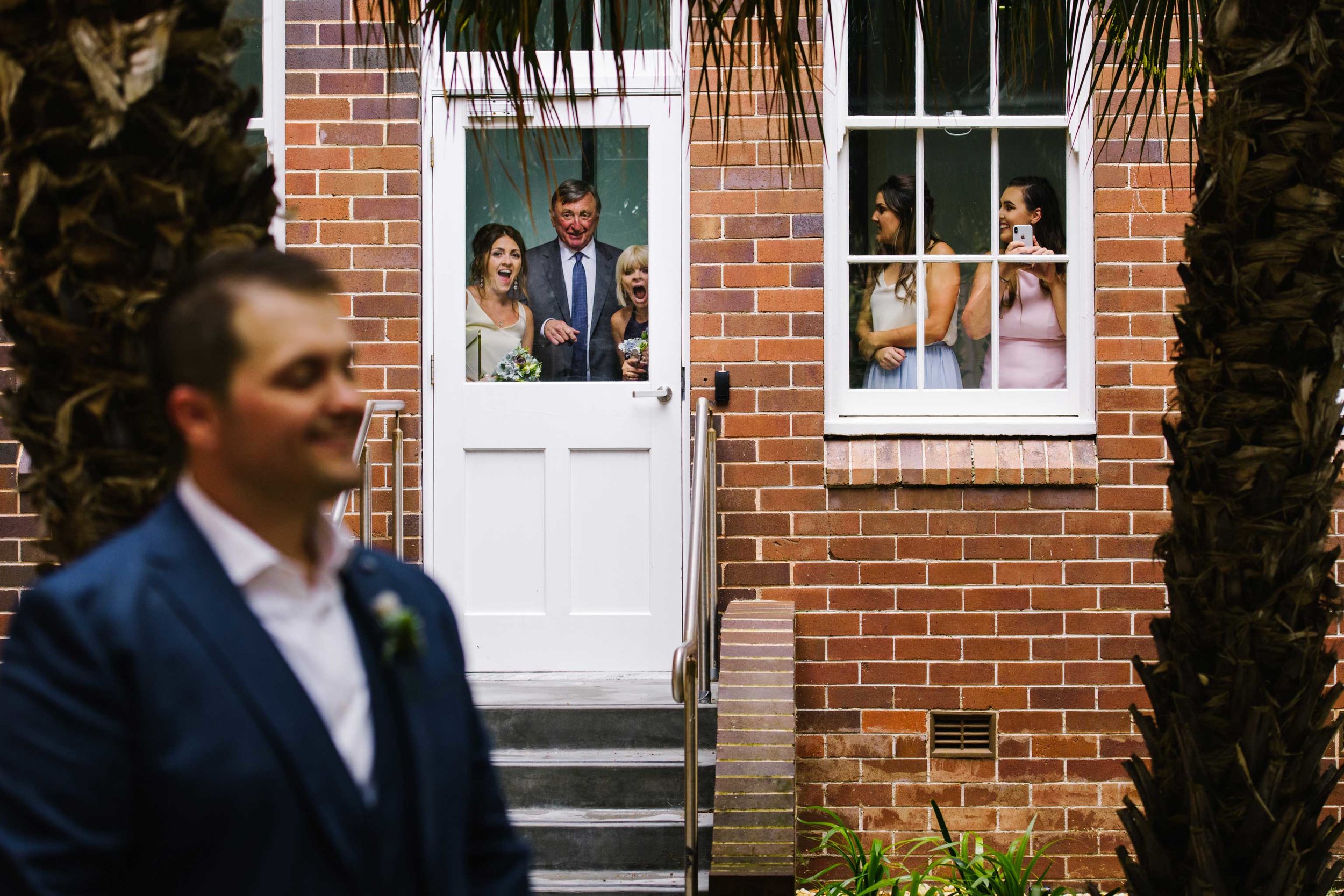 Family looking out window at groom before first look