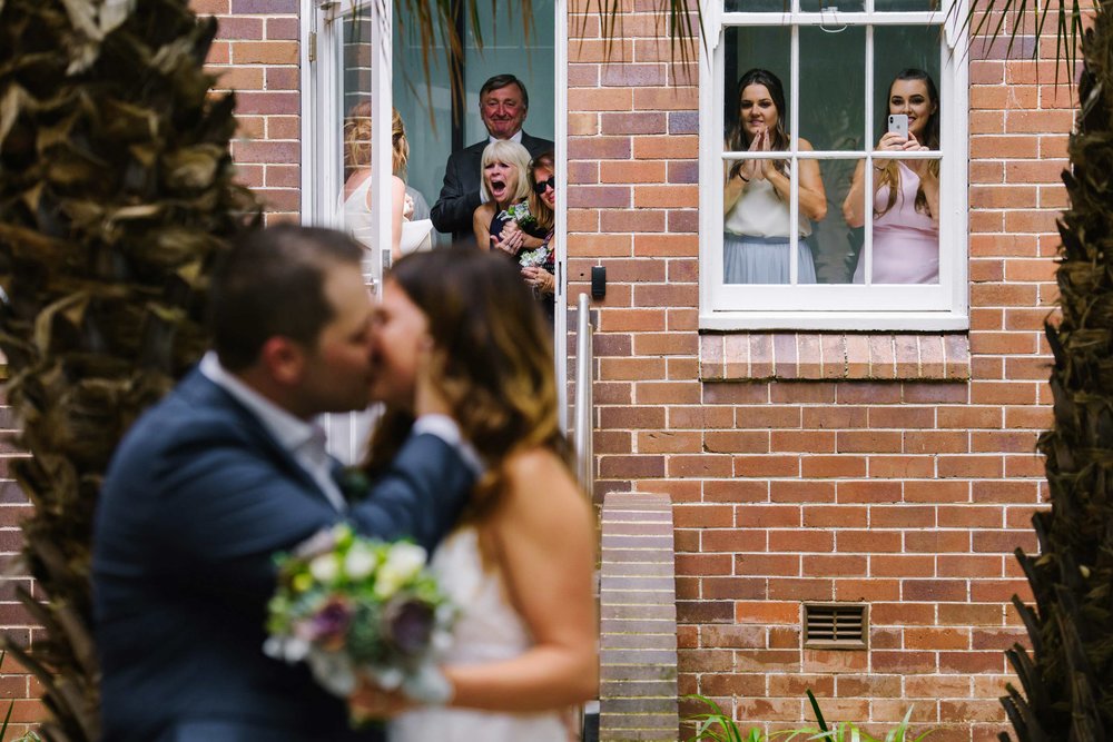 Bride and groom kiss after first look while family looks on